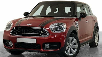 Ein roter Mini Countryman SE Plug-in-Hybrid steht vor einer weißen Wand