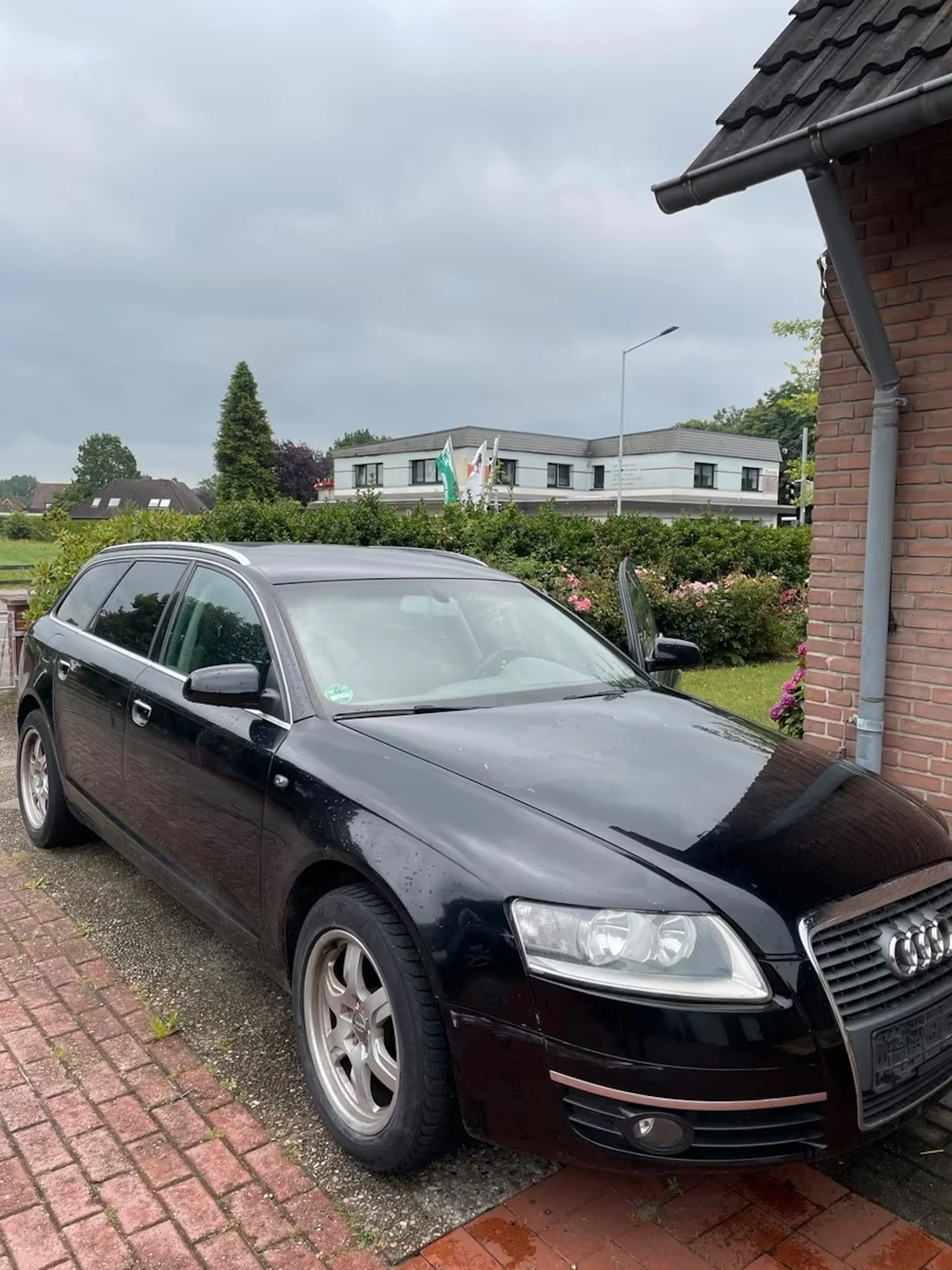 Schwarzer Audi A6 C6 auf gepflastertem Weg