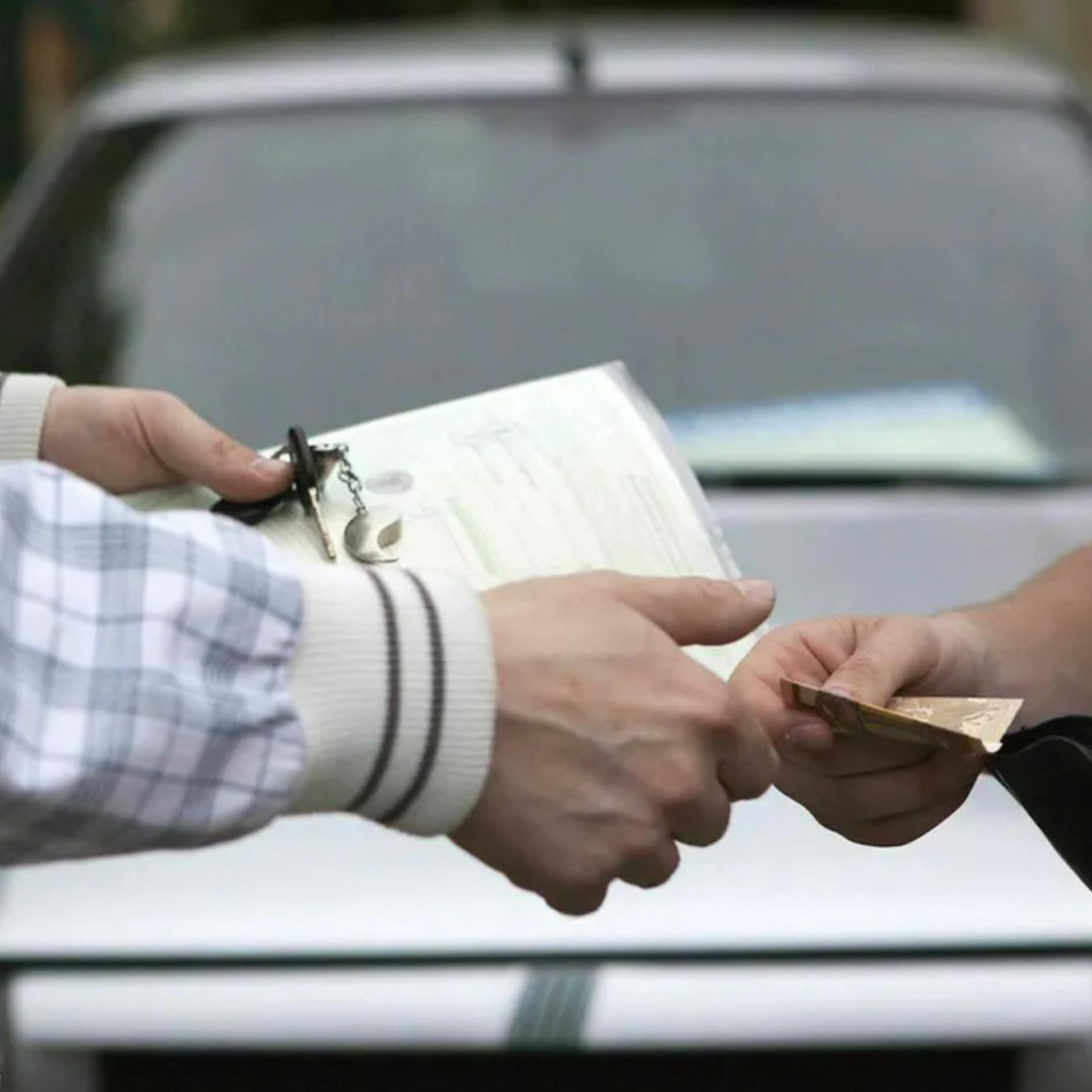 Sicherheit beim Autokauf: Eine Person übergibt einer anderen Geld und erhält im Gegenzug Fahrzeugpapiere und Autoschlüssel