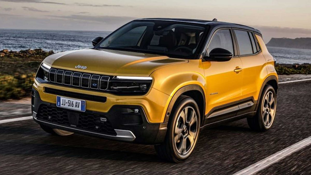 Ein goldenes Jeep Avenger Elektroauto fährt eine Küstenstraße entlang.