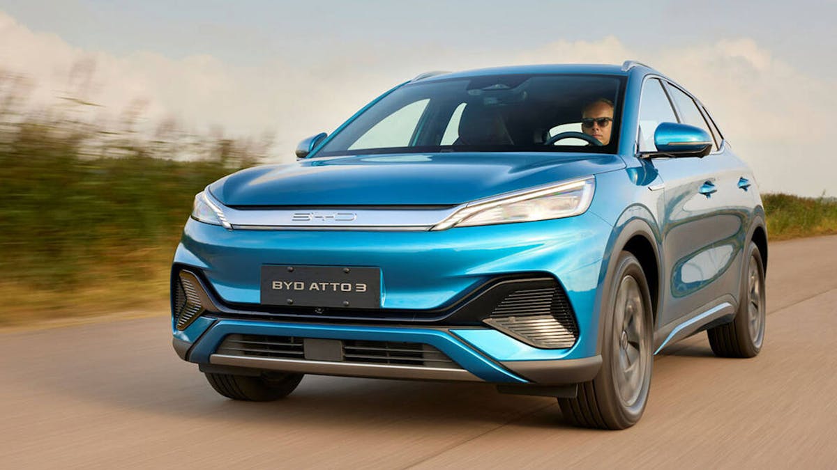 Ein blauer BYD Atto 3 fährt eine Landstraße entlang.