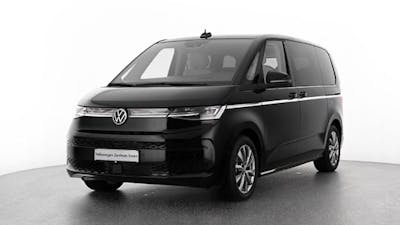 Ein schwarzer VW T7 eHybrid Multivan steht vor einer weißen Wand.
