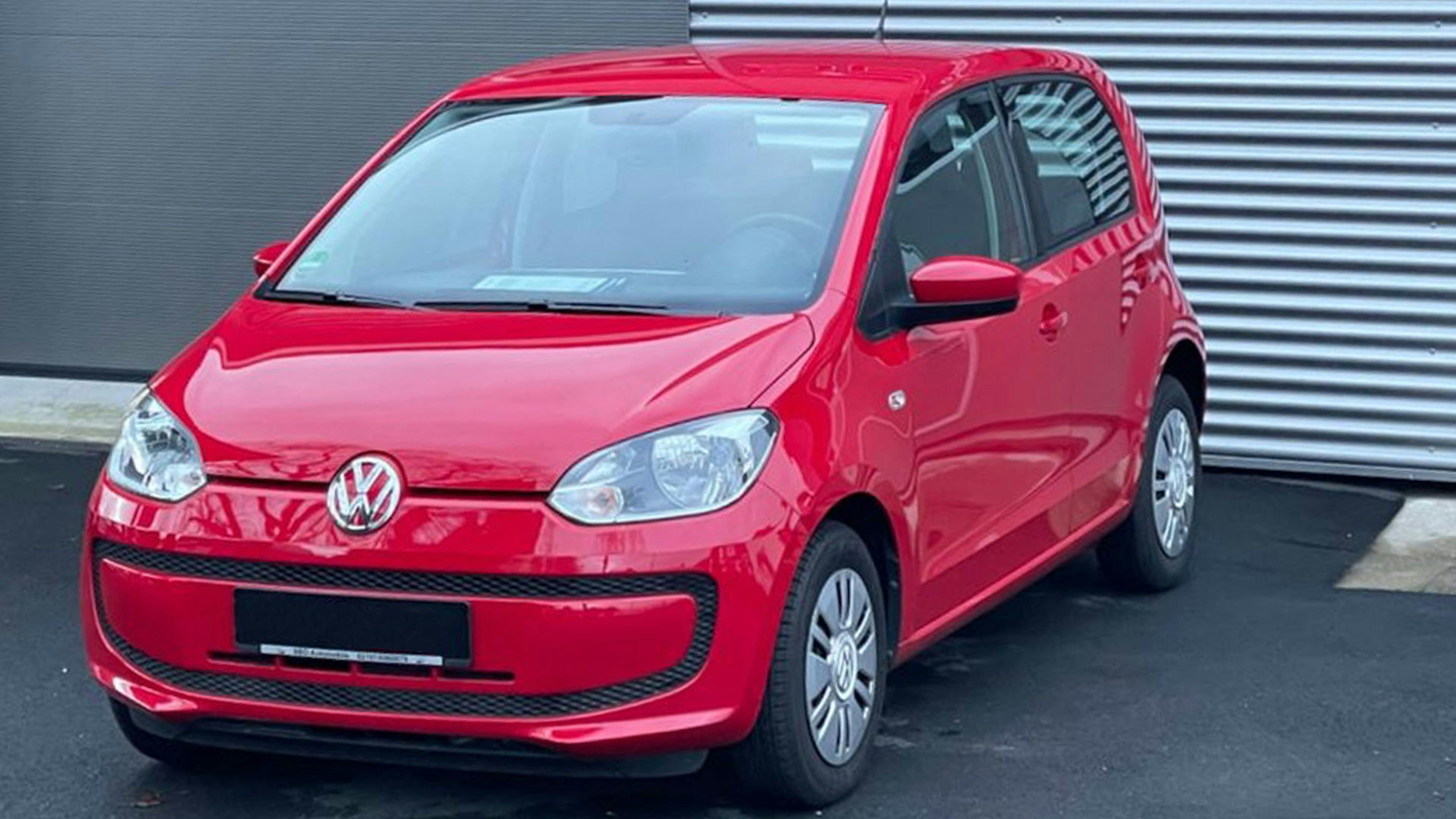 Ein roter VW-up!-Kleinstwagen steht vor einer grauen Wand.