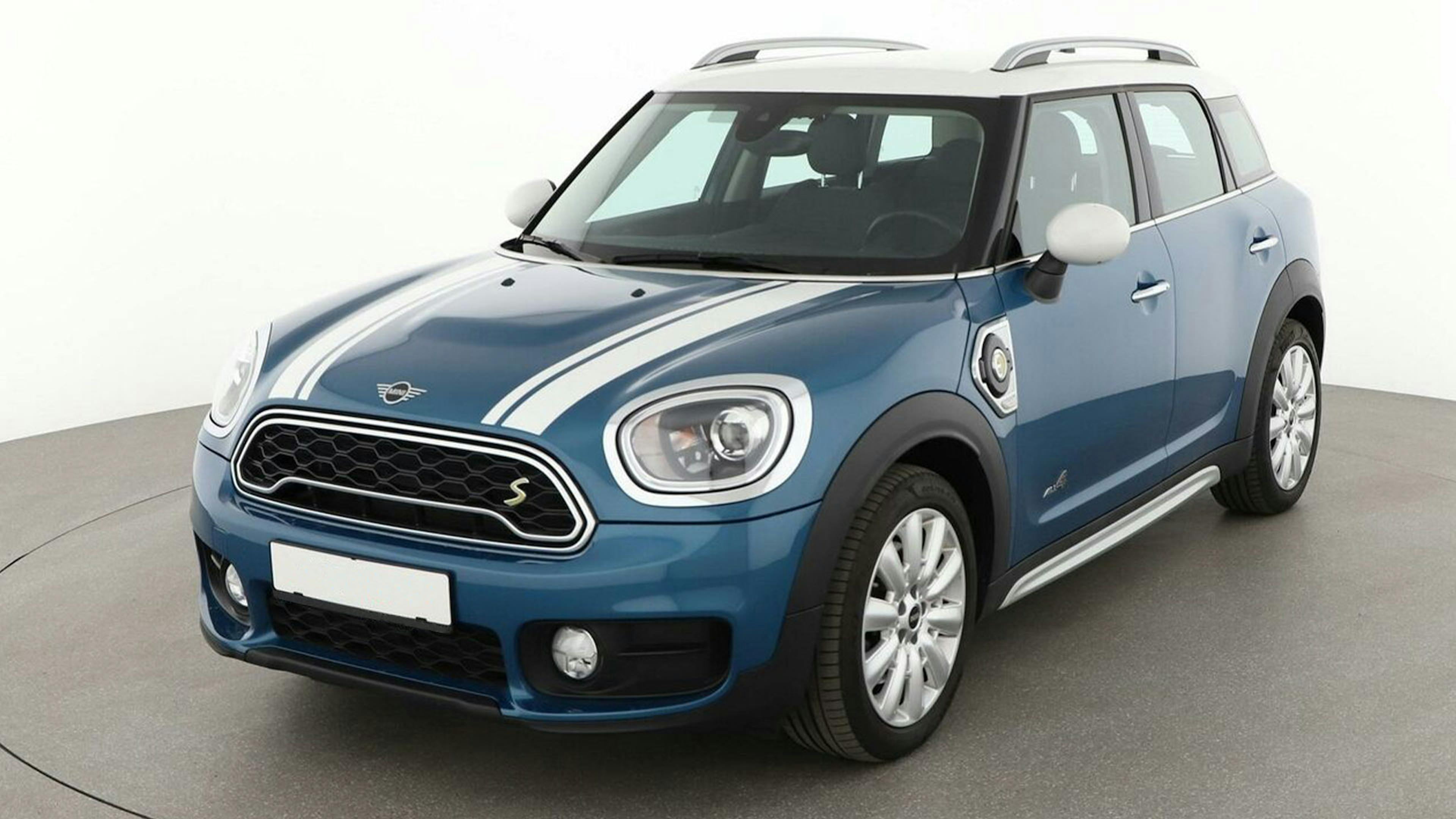 Ein blauer Mini Countryman Hybrid-SUV mit weißen Streifen steht vor einer weißen Wand