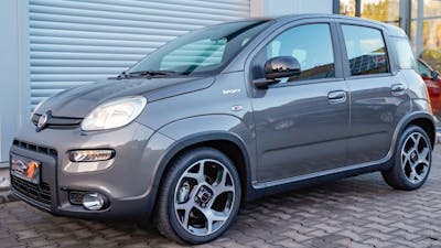 Ein silberner Fiat Panda steht vor einem Rolltor.