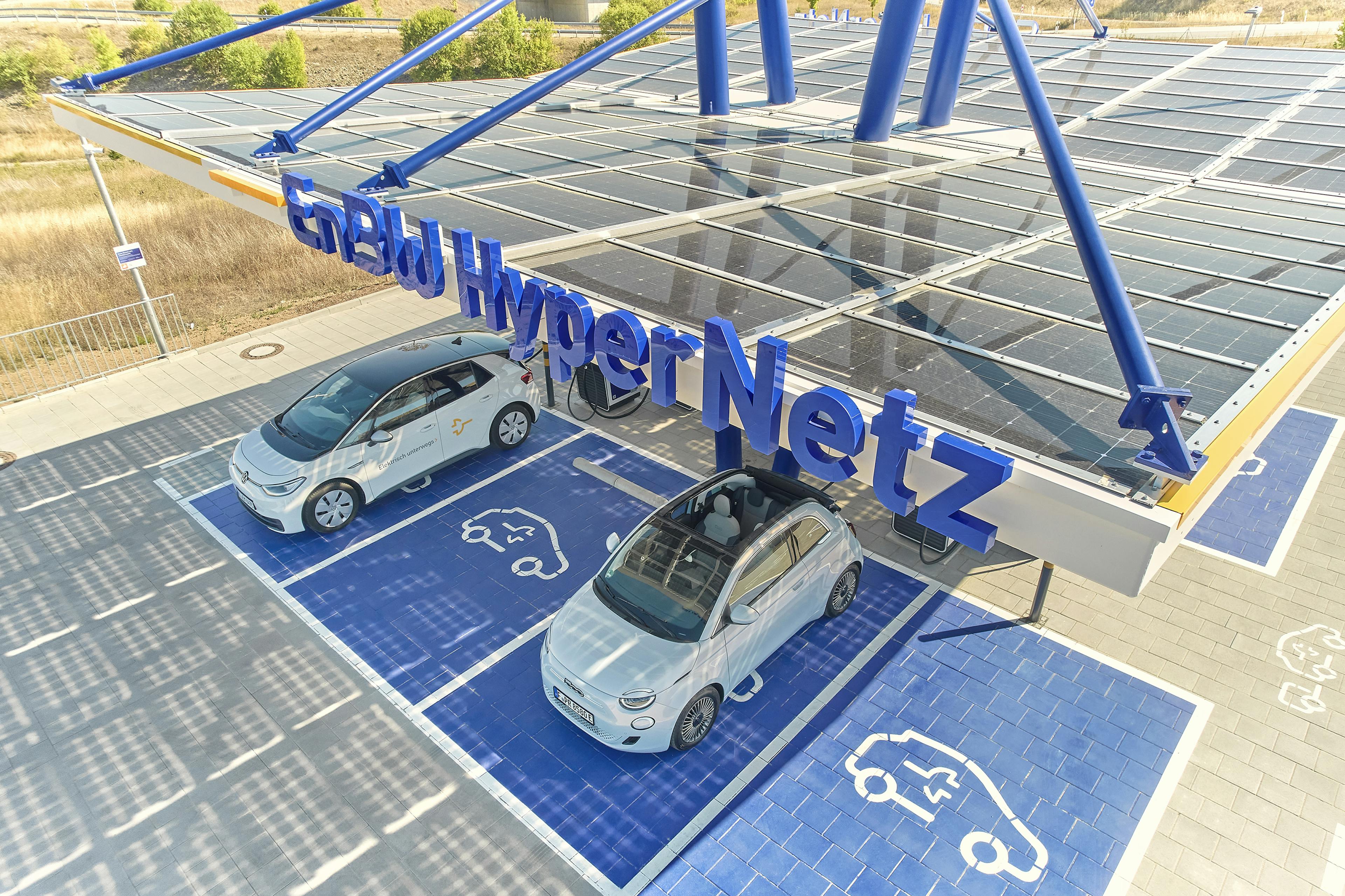 A VW ID.3 and a Fiat 500e are parked under the solar roof of an EnBW charging park.