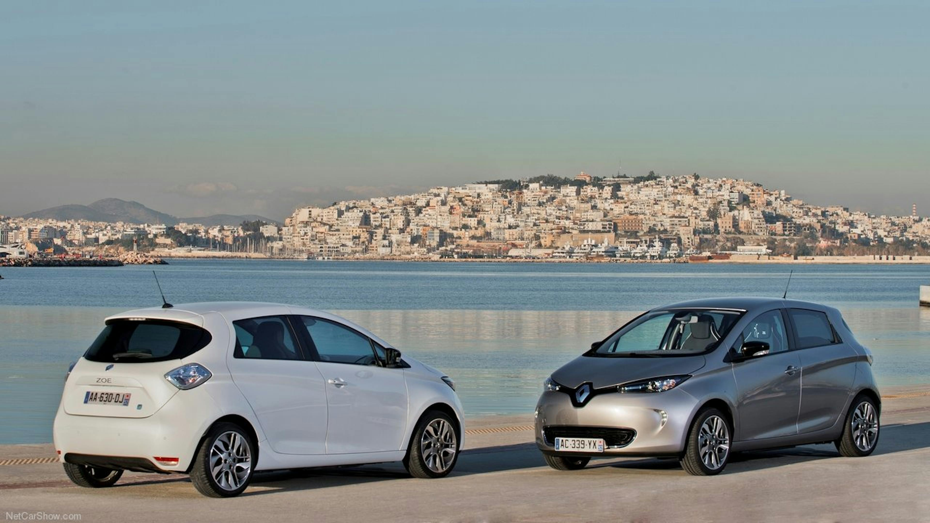 Eine weißer und ein grauer Renault Zoe stehen am Ufer. 