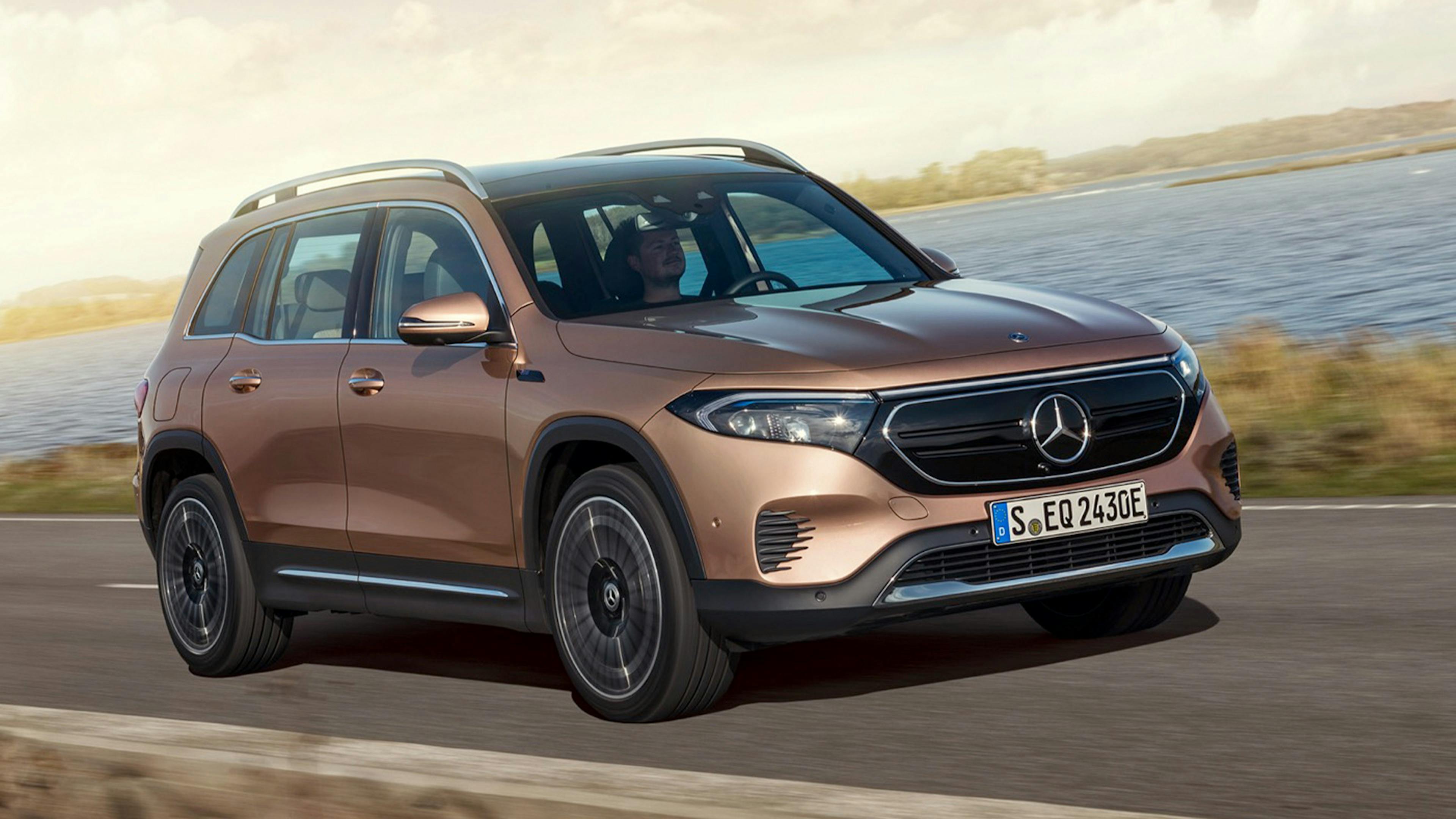 Ein braunes Mercedes-Benz-EQB-Elektroauto mit Allradantrieb fährt eine Landstraße entlang.