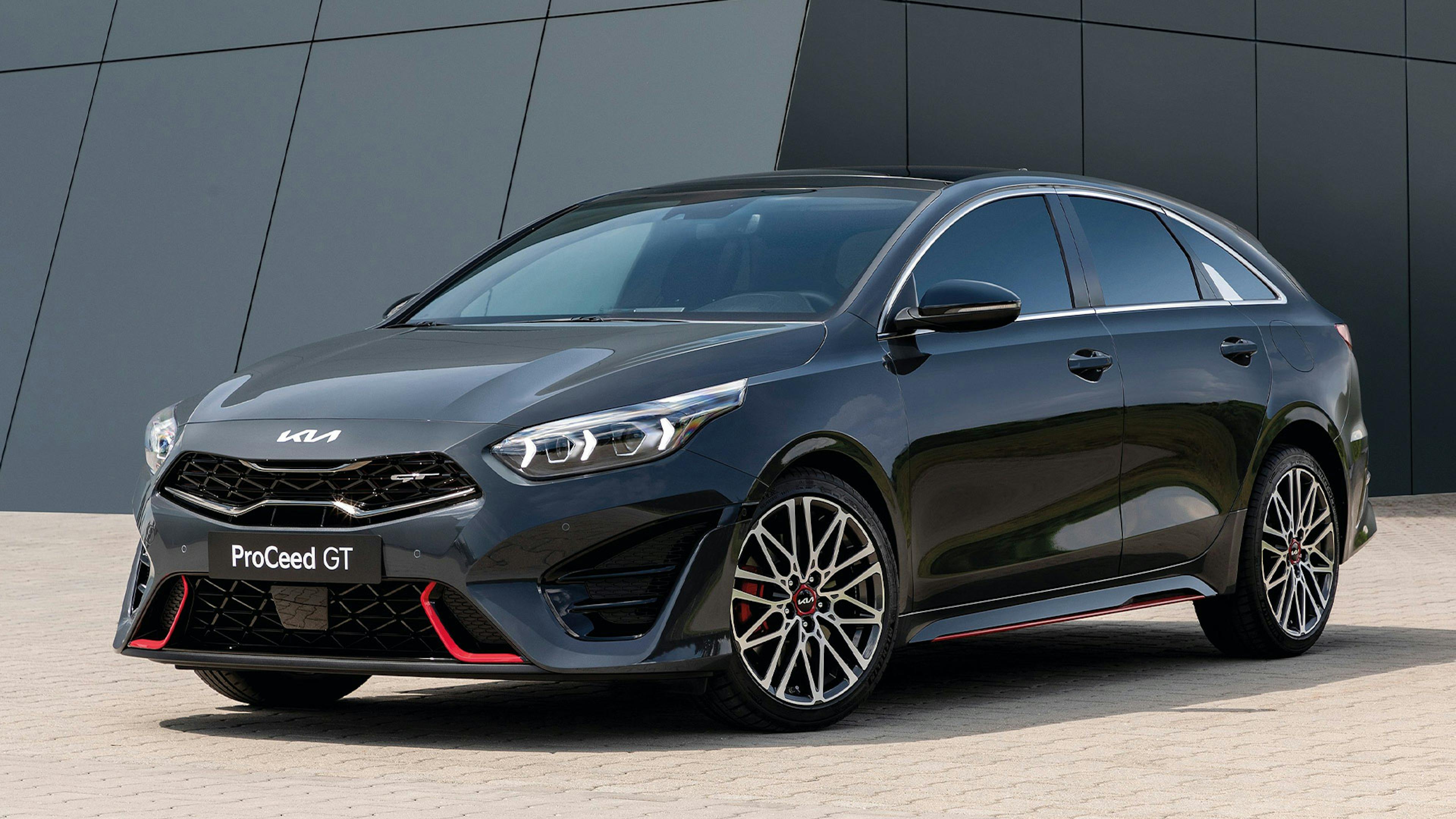Ein schwarzer Kia ProCeed GT steht vor einem grauen Gebäude.