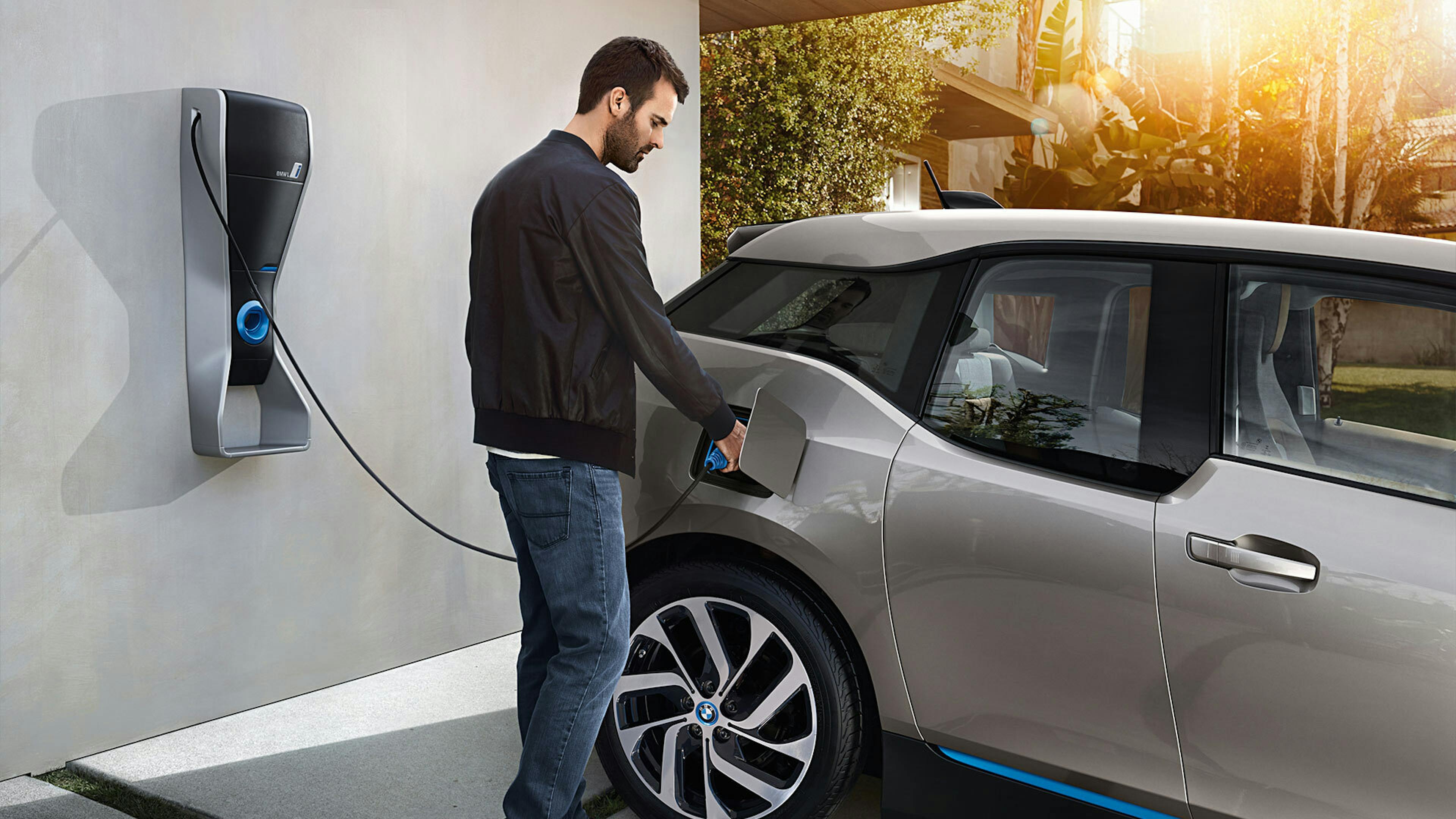 Ein Mann schließt seinen BMW i3 an eine Wallbox an.