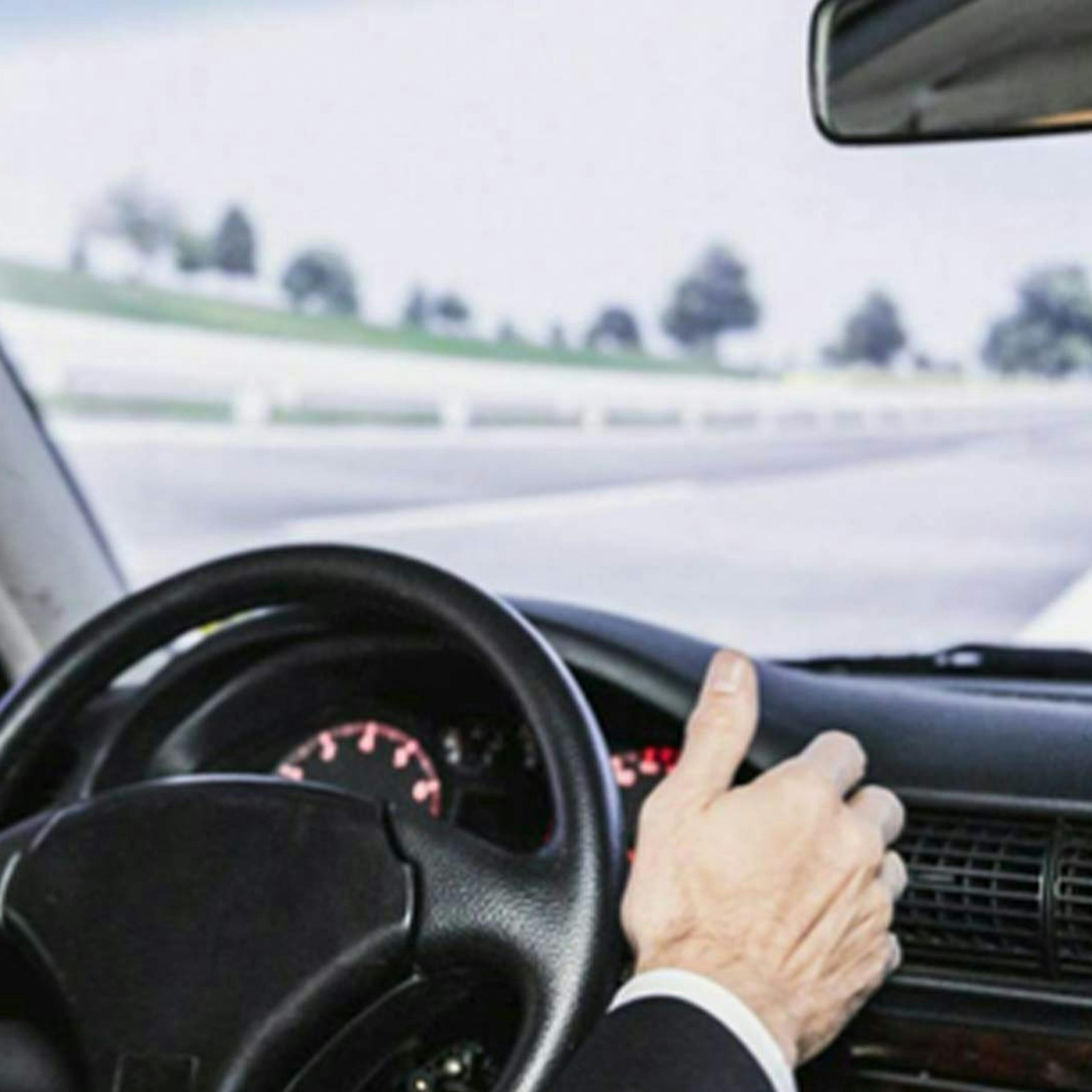 Eine Person sitzt am Steuer eines autonom fahrenden Pkw 