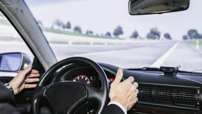 Eine Person sitzt am Steuer eines autonom fahrenden Pkw