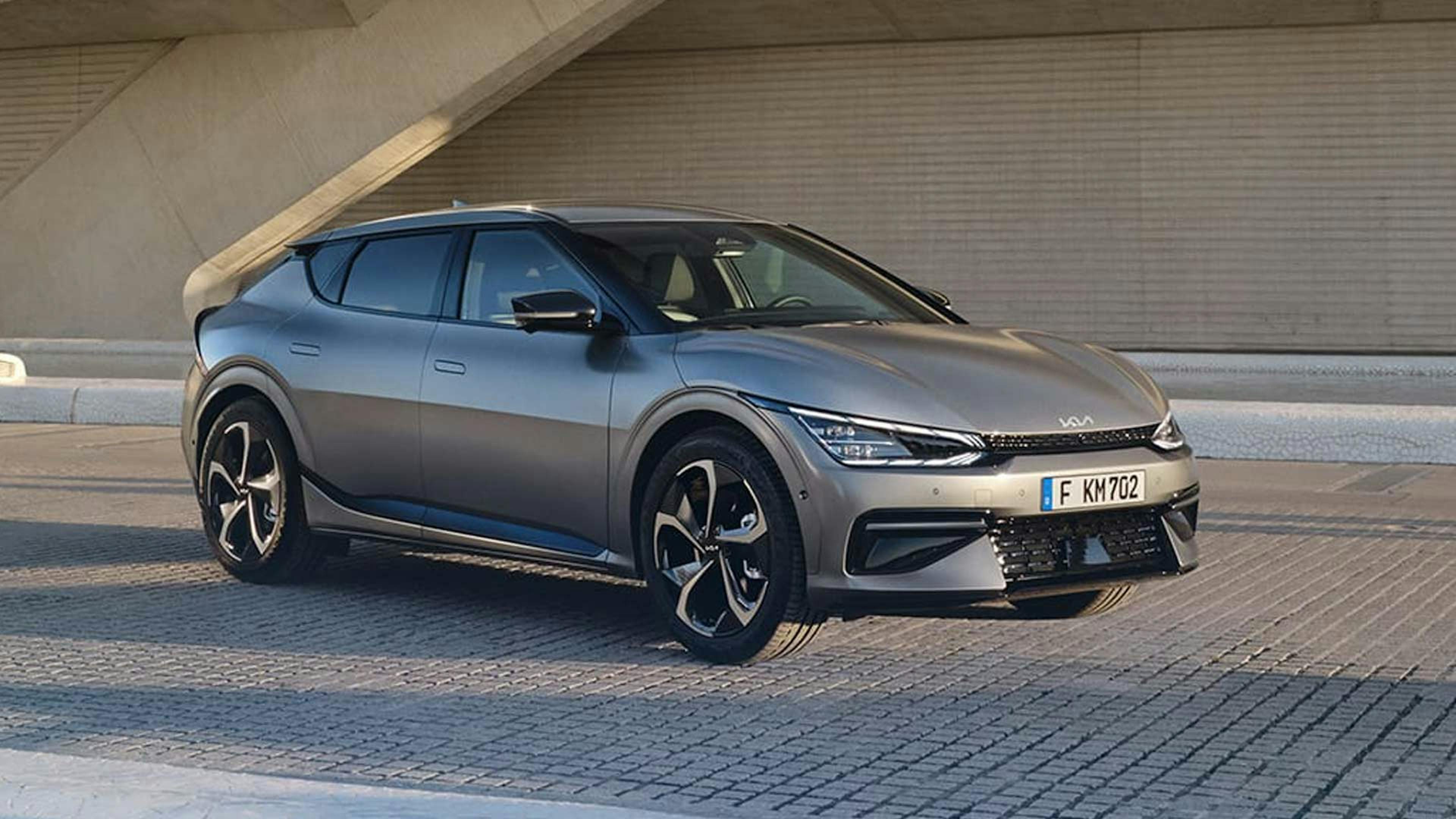 Ein grauer Kia EV6 steht vor einem grauen Gebäude.