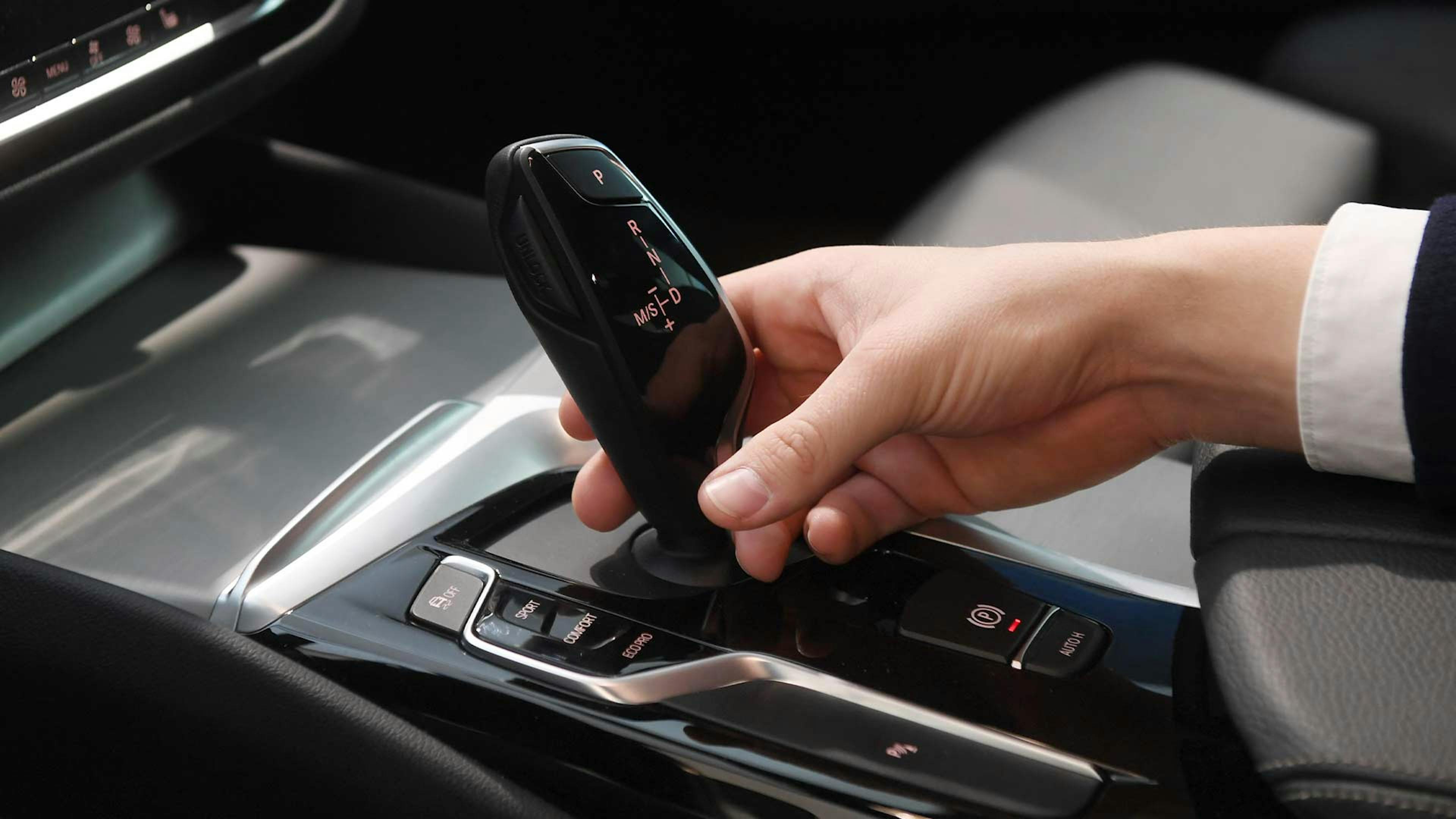 Eine Person bedient die Schaltung eines Pkw mit Automatikgetriebe.