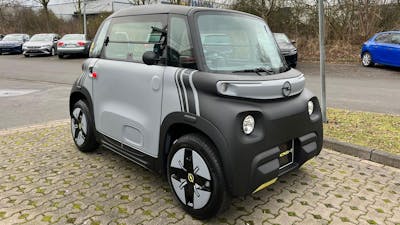 Ein grau-schwarzes Opel Rocks-e Microcar steht auf einem Parkplatz.