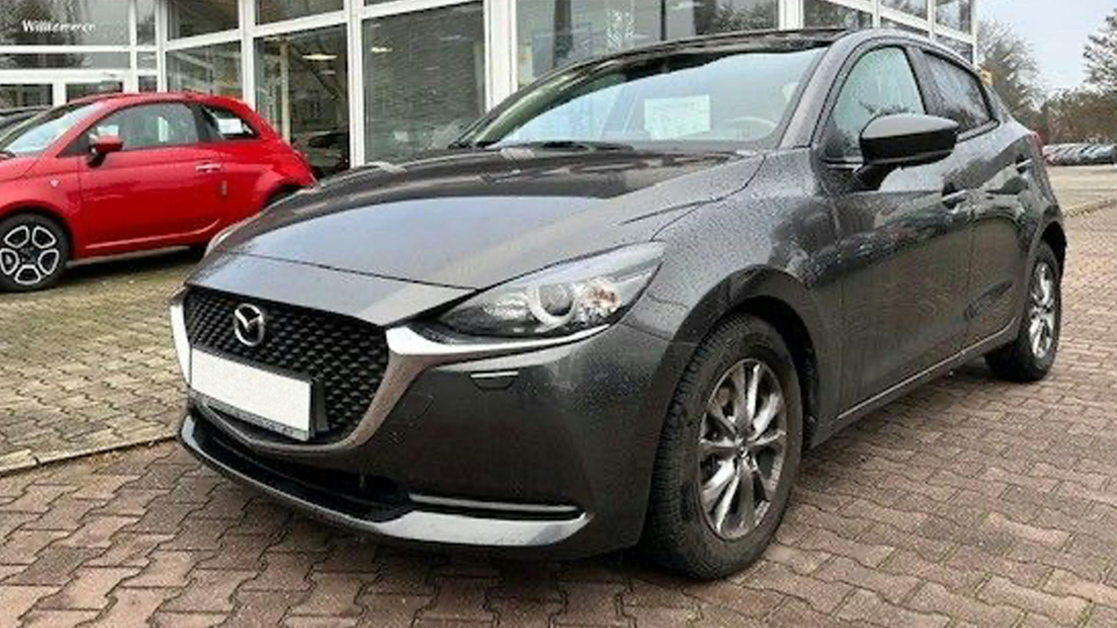 Ein schwarzer Mazda 2 DJ steht vor einem Autohaus.