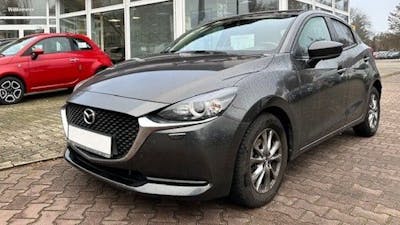 Ein schwarzer Mazda 2 DJ steht vor einem Autohaus.
