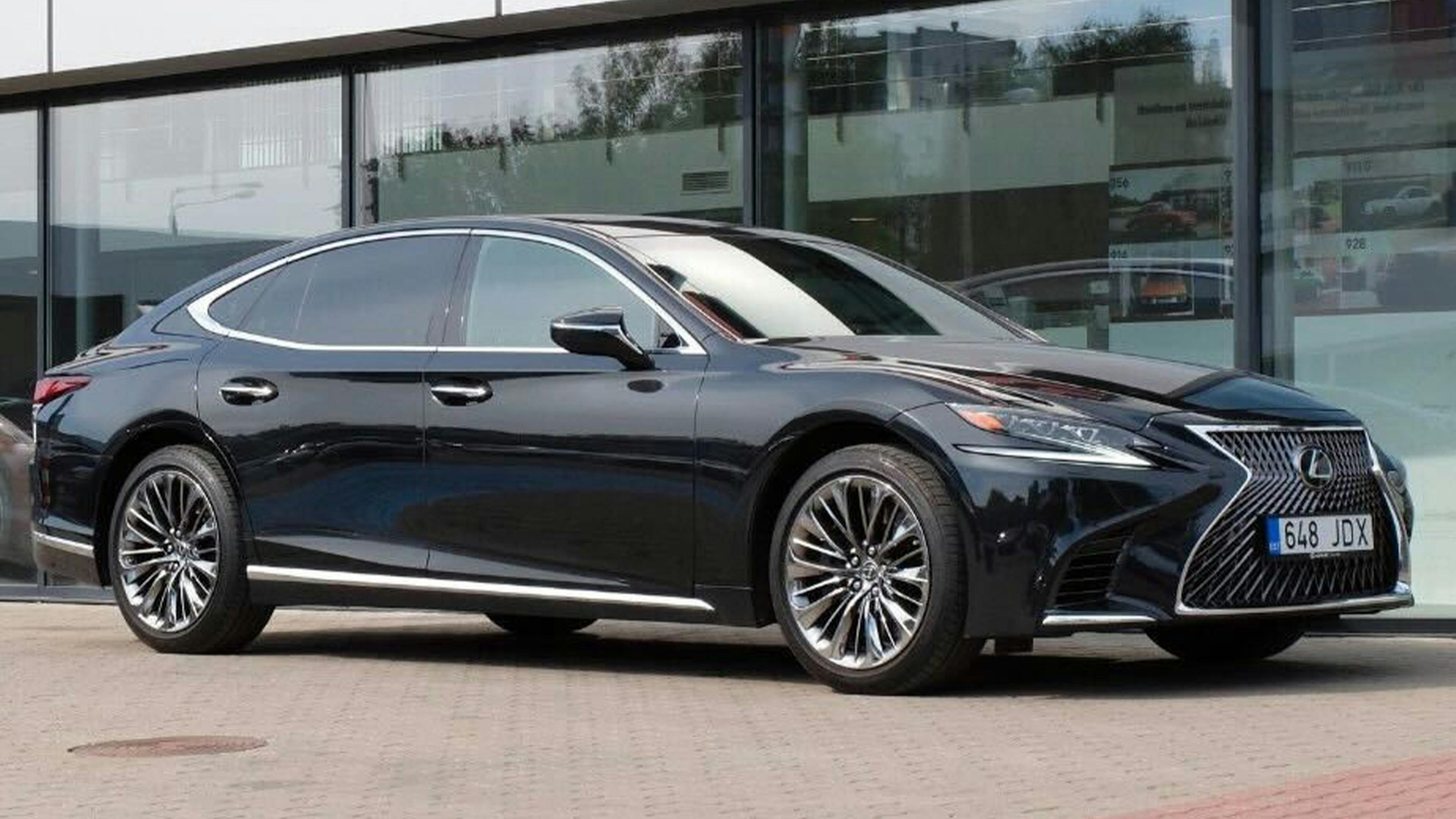Ein schwarzer Lexus LS steht vor einem Gebäude mit Glasfassade.