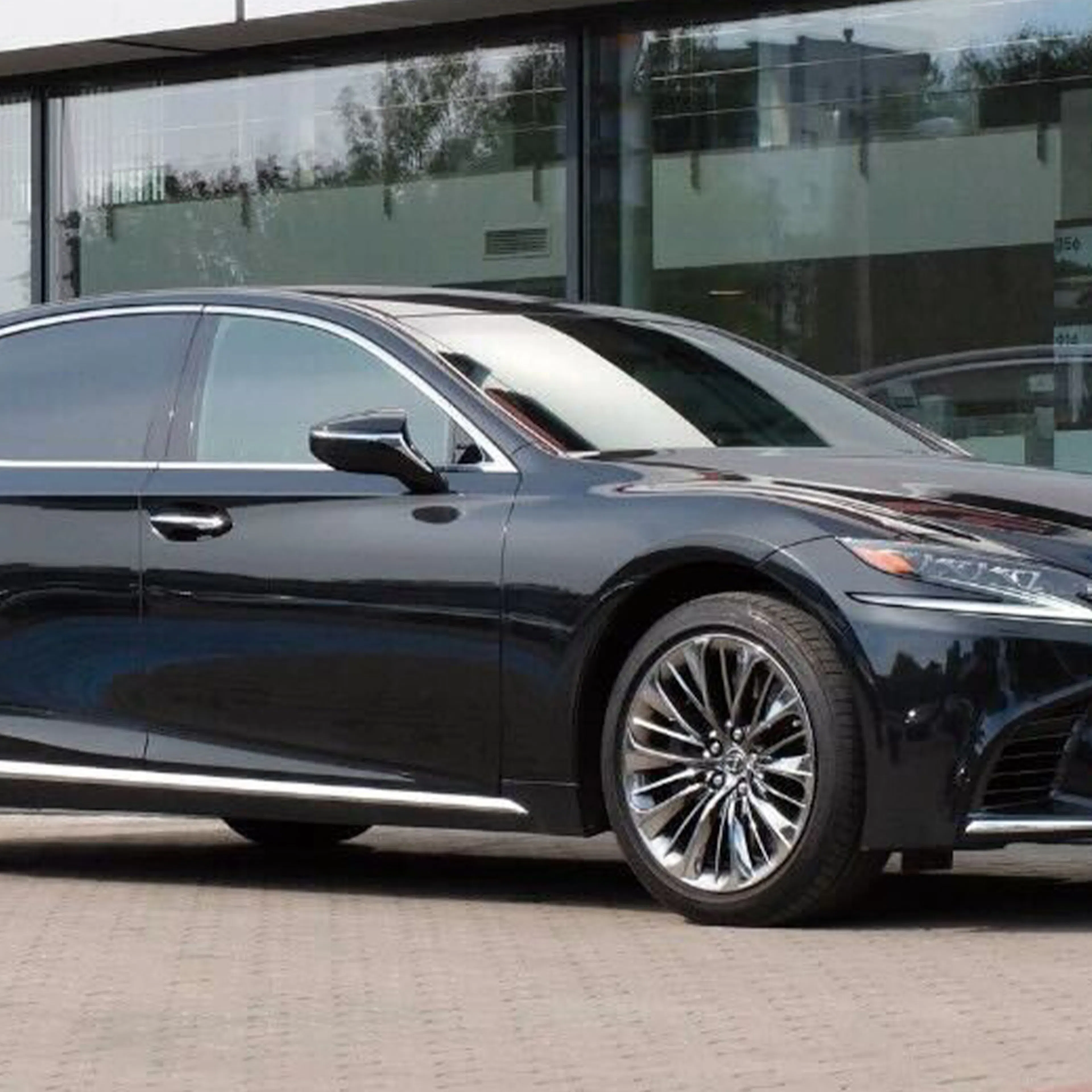 Ein schwarzer Lexus LS steht vor einem Gebäude mit Glasfassade.