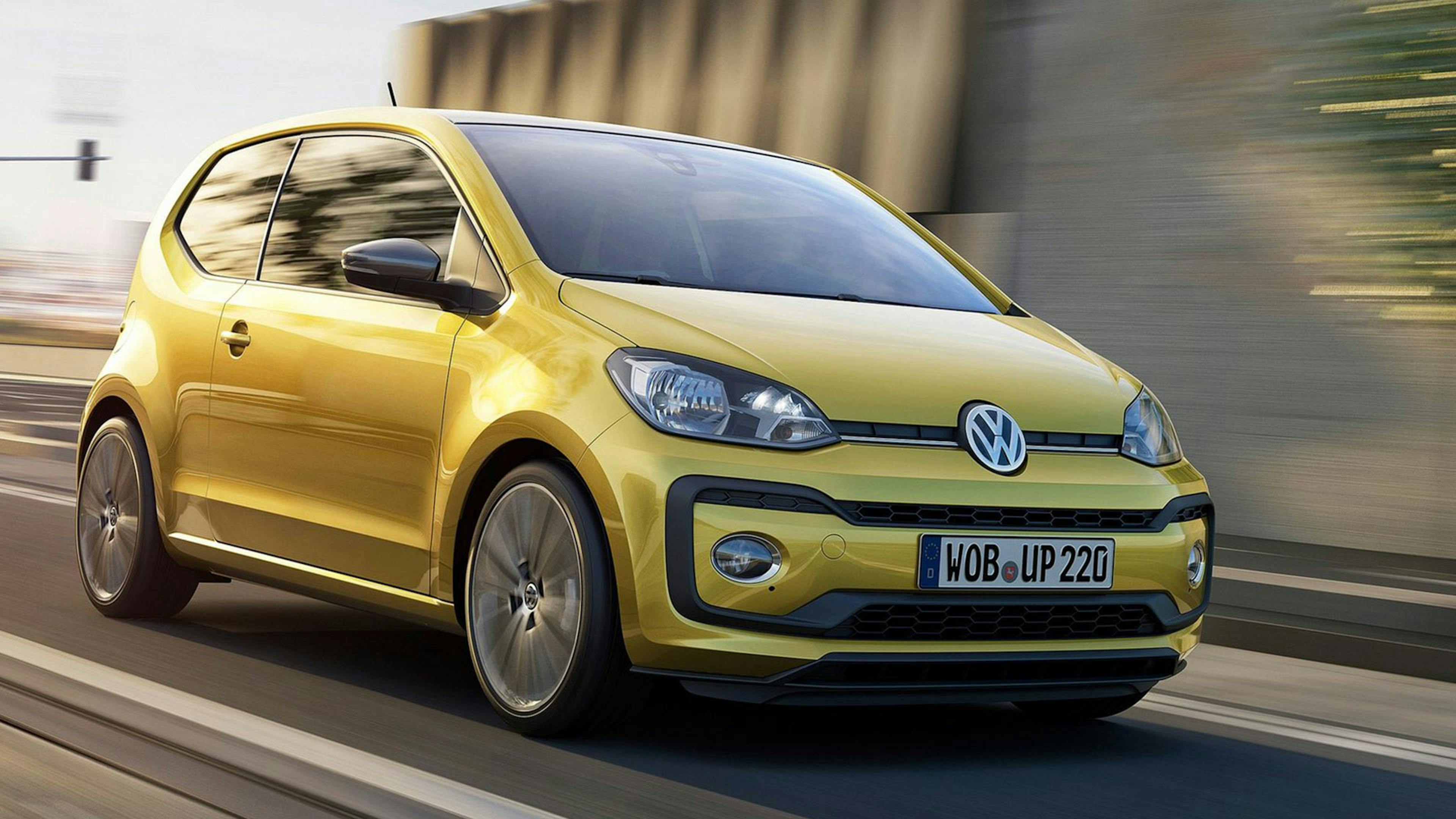 Ein gelber VW up! Kleinstwagen fährt eine Straße entlang.