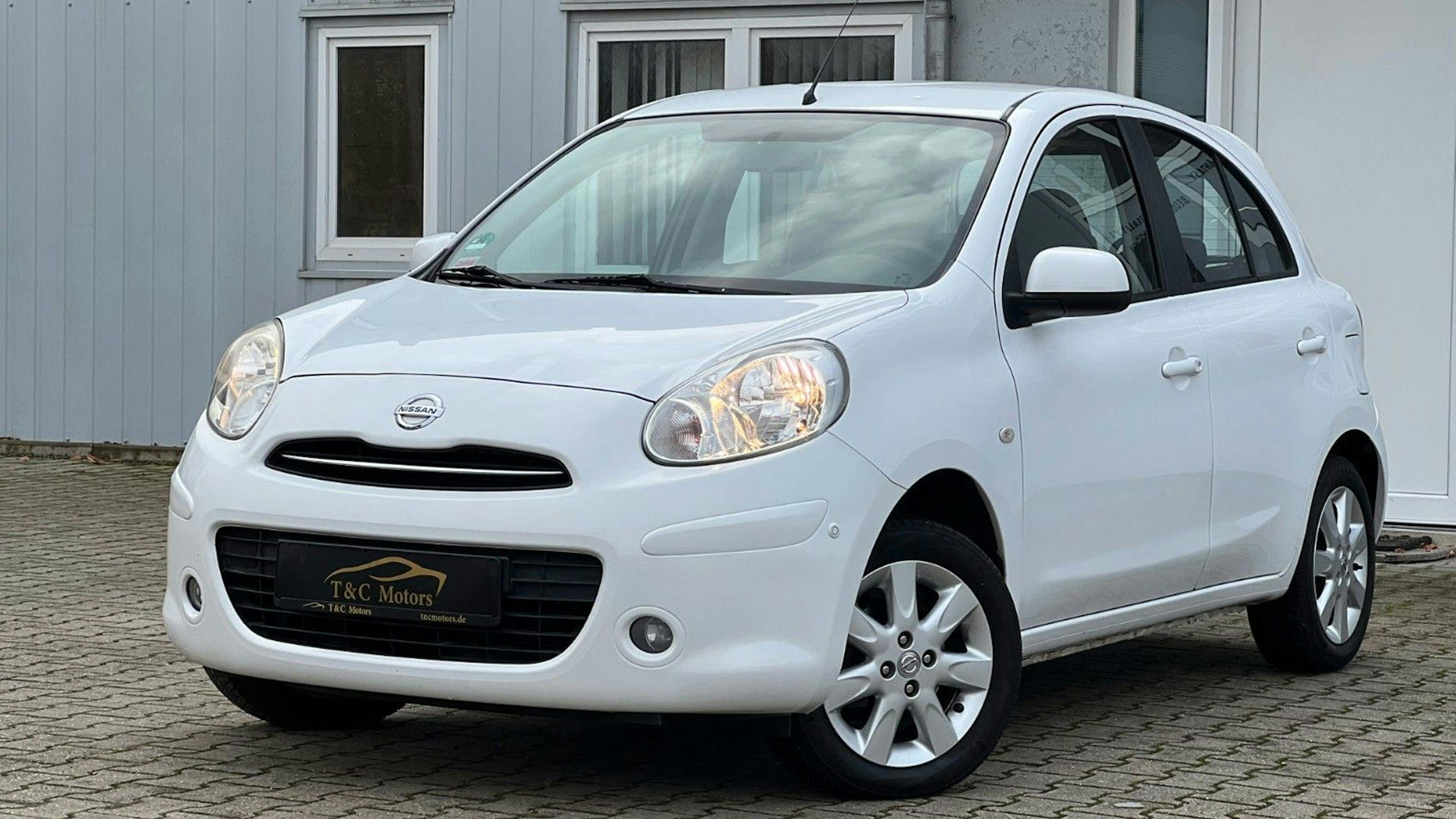 Ein weißer Nissan Micra steht vor einem weißen Haus.