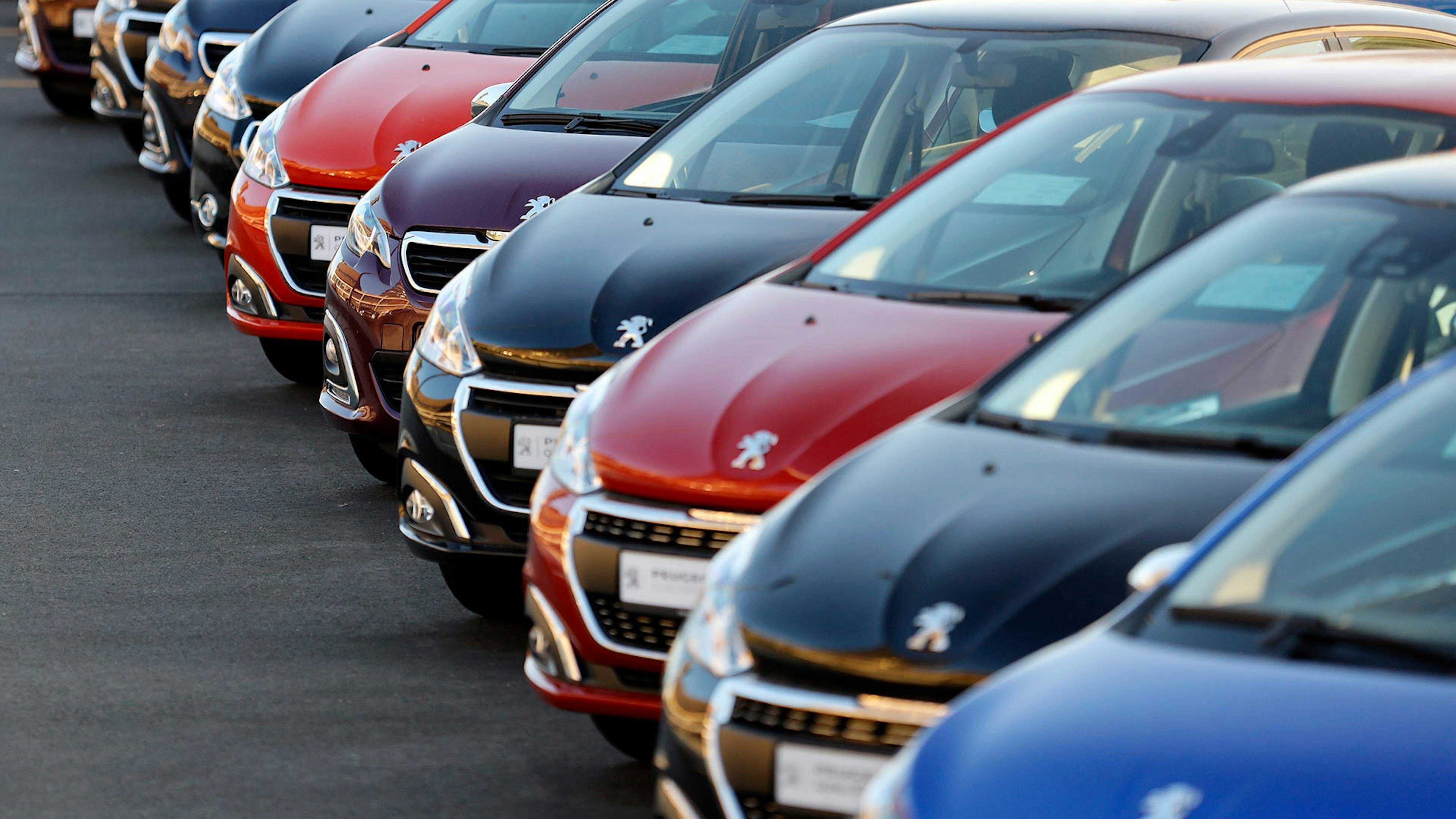 Mehrere Neuwagen und Lagerfahrzeuge stehen nebeneinander auf einem Parkplatz.