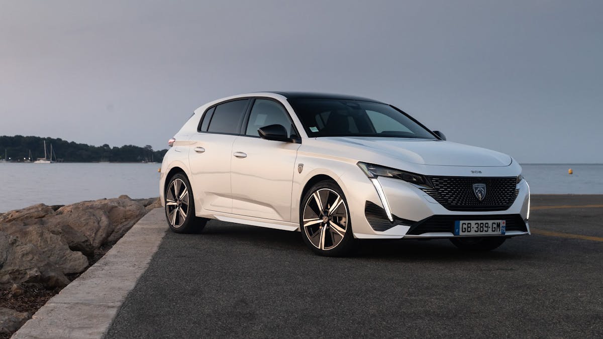Ein weißer Peugeot 308 steht am Rand eines Gewässers.