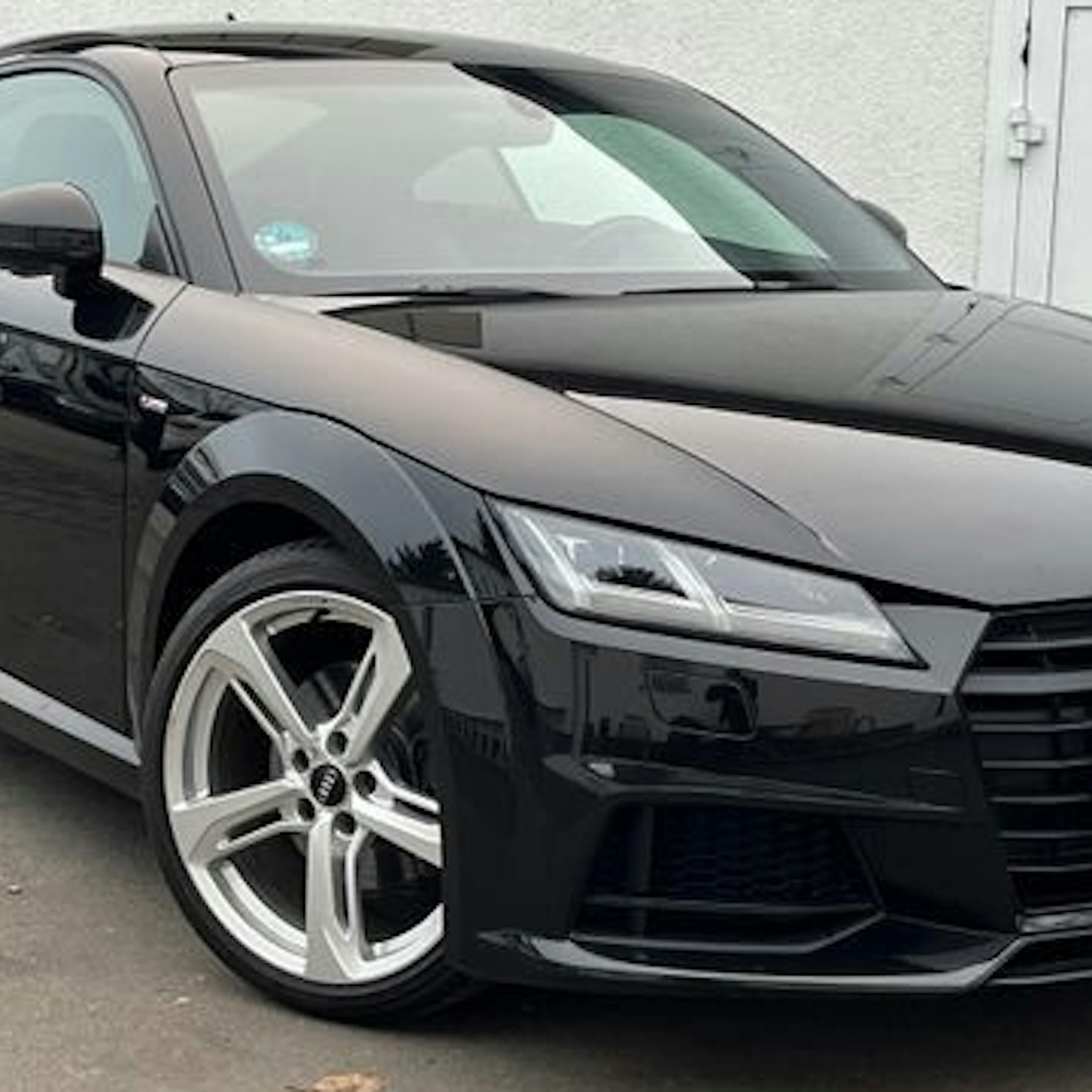A black Audi TT in front of a building.