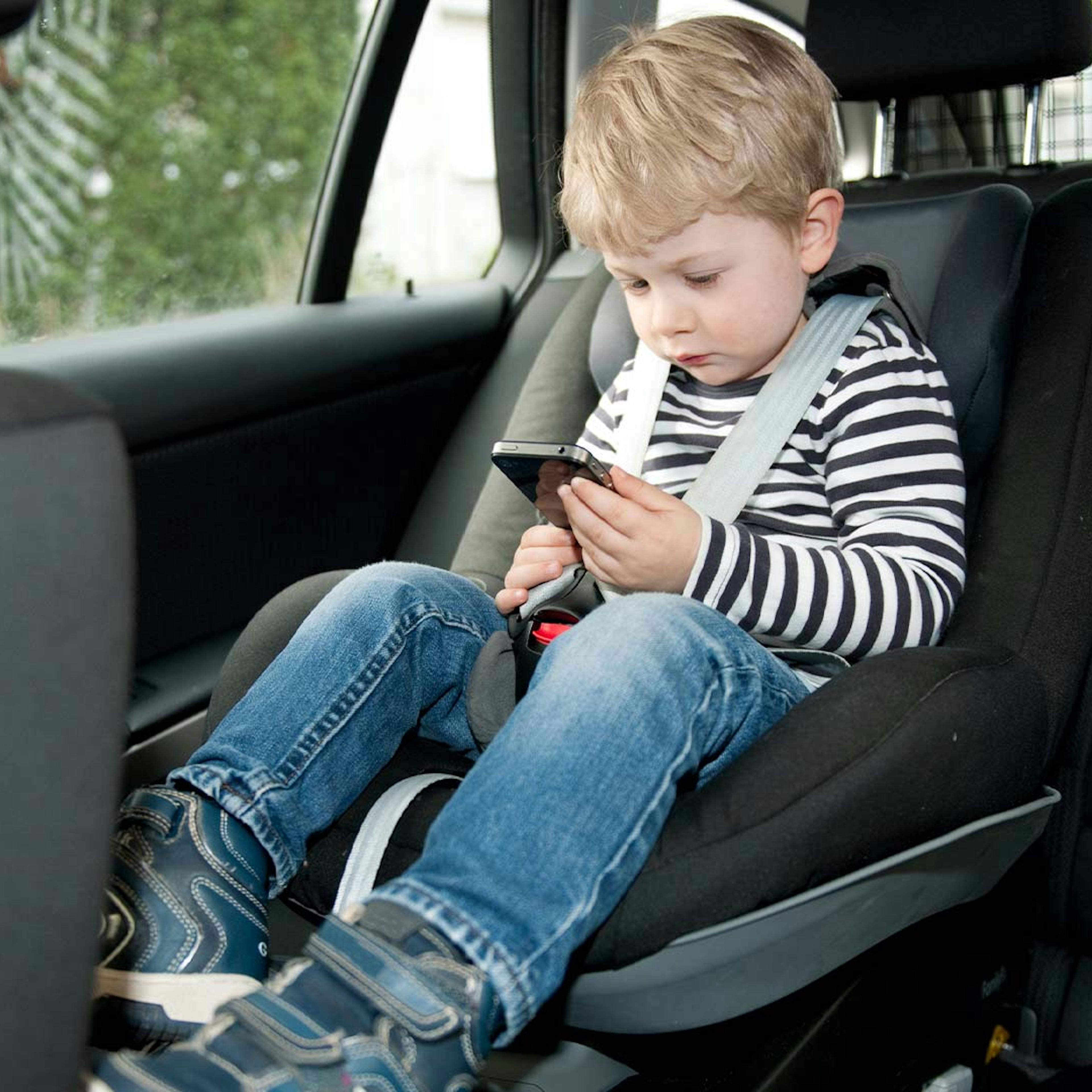 Ein kleiner Junge sitzt angeschnallt in einem Isofix-Kindersitz in einem Auto.