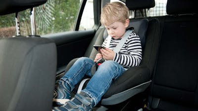 Ein kleiner Junge sitzt angeschnallt in einem Isofix-Kindersitz in einem Auto.