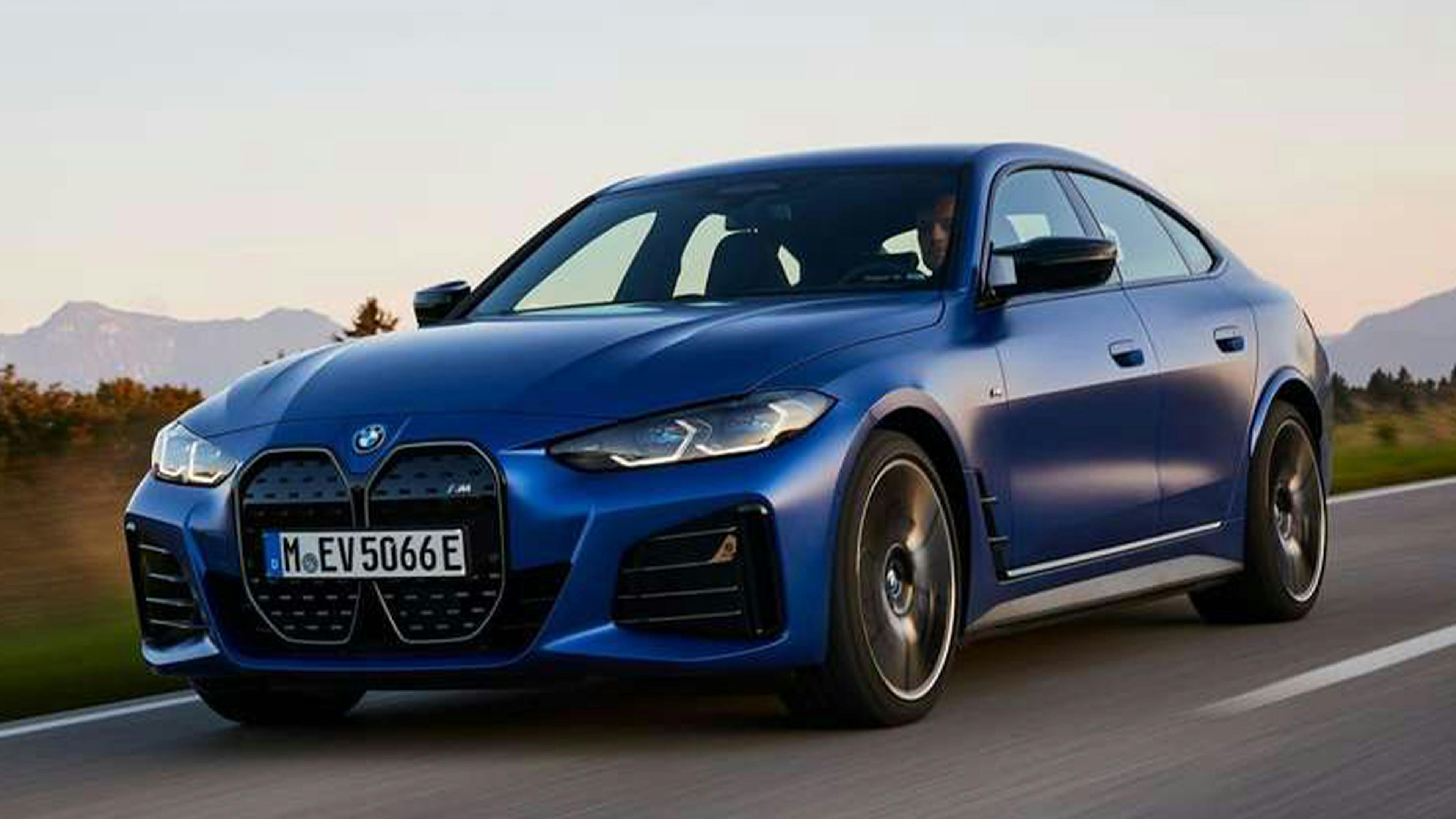 Ein blauer BMW i4 fährt eine Landstraße entlang.