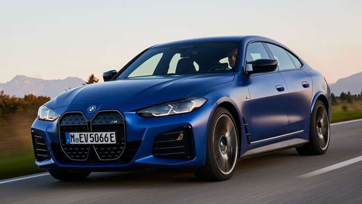 Ein blauer BMW i4 fährt eine Landstraße entlang.
