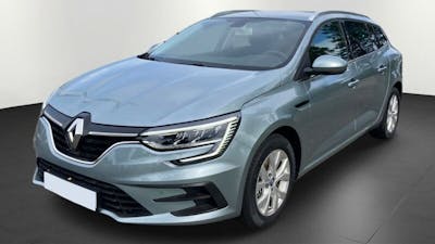 Ein grauer Renault Mégane Grandtour eTech steht vor einer weißen Wand.