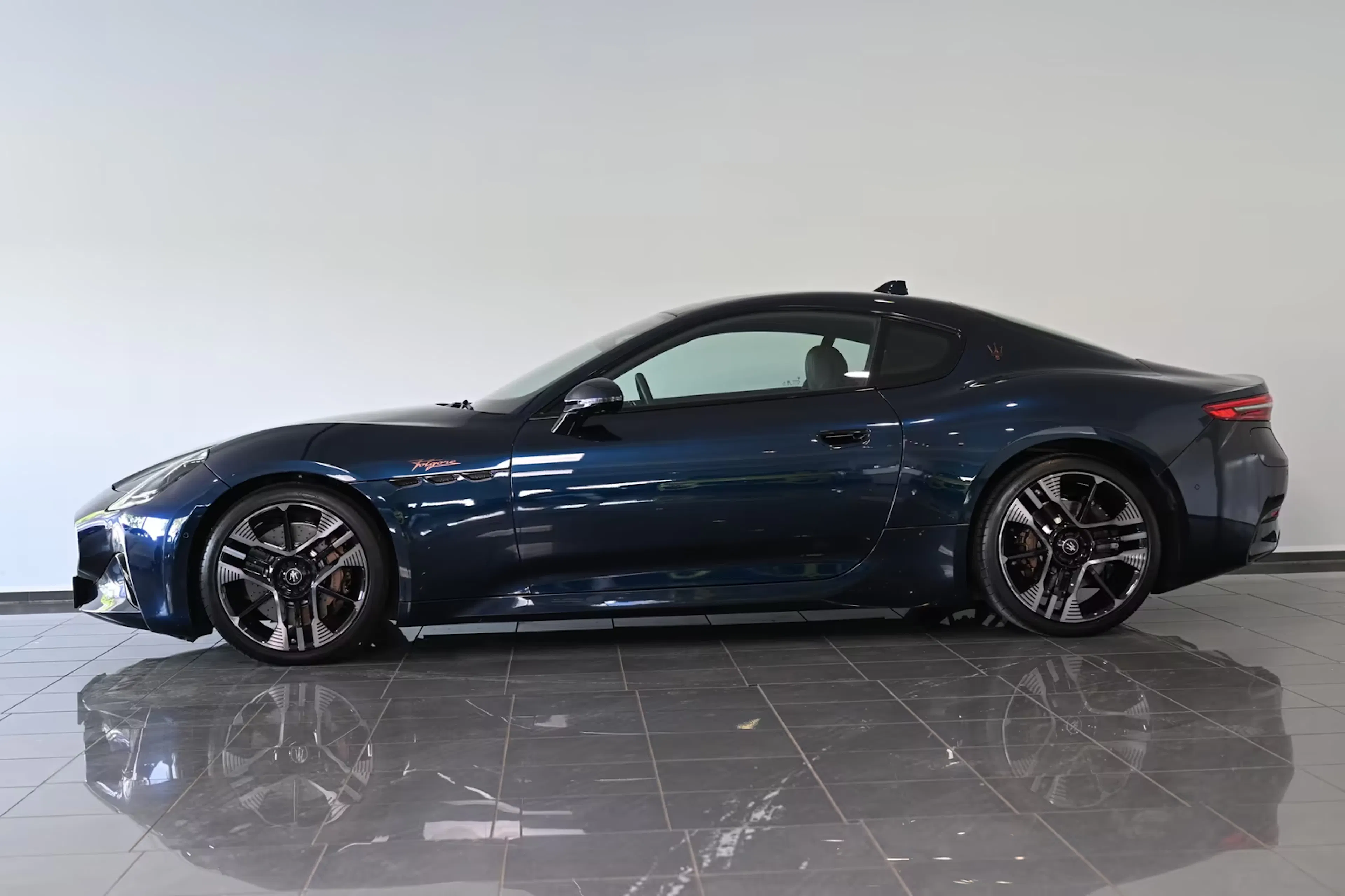 Ein Maserati Granturismo Folgore steht auf einer reflektierenden Fläche.