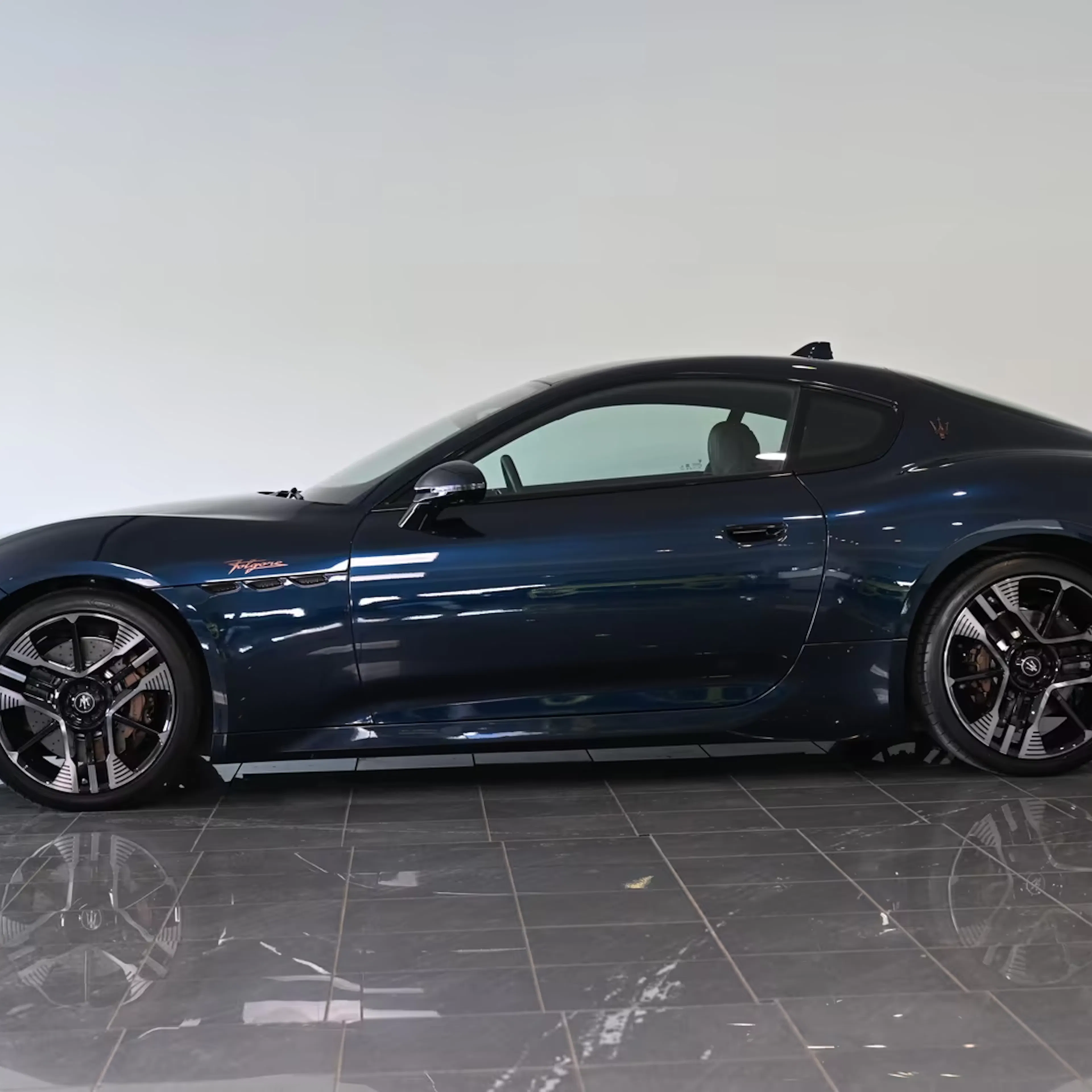 Ein Maserati Granturismo Folgore steht auf einer reflektierenden Fläche.