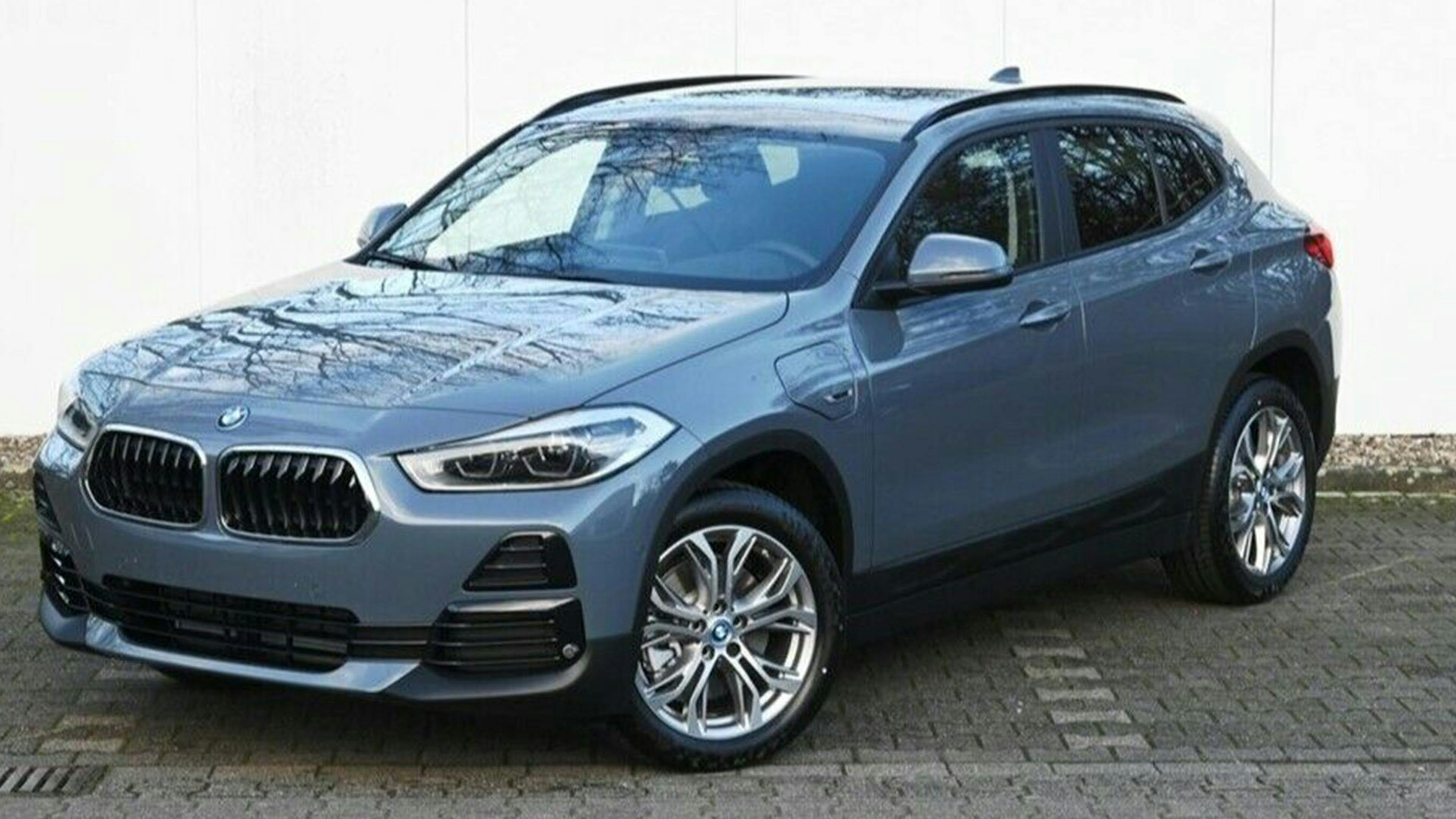 Ein blauer BMW X2 25e Hybrid-SUV steht vor einer weißen Wand