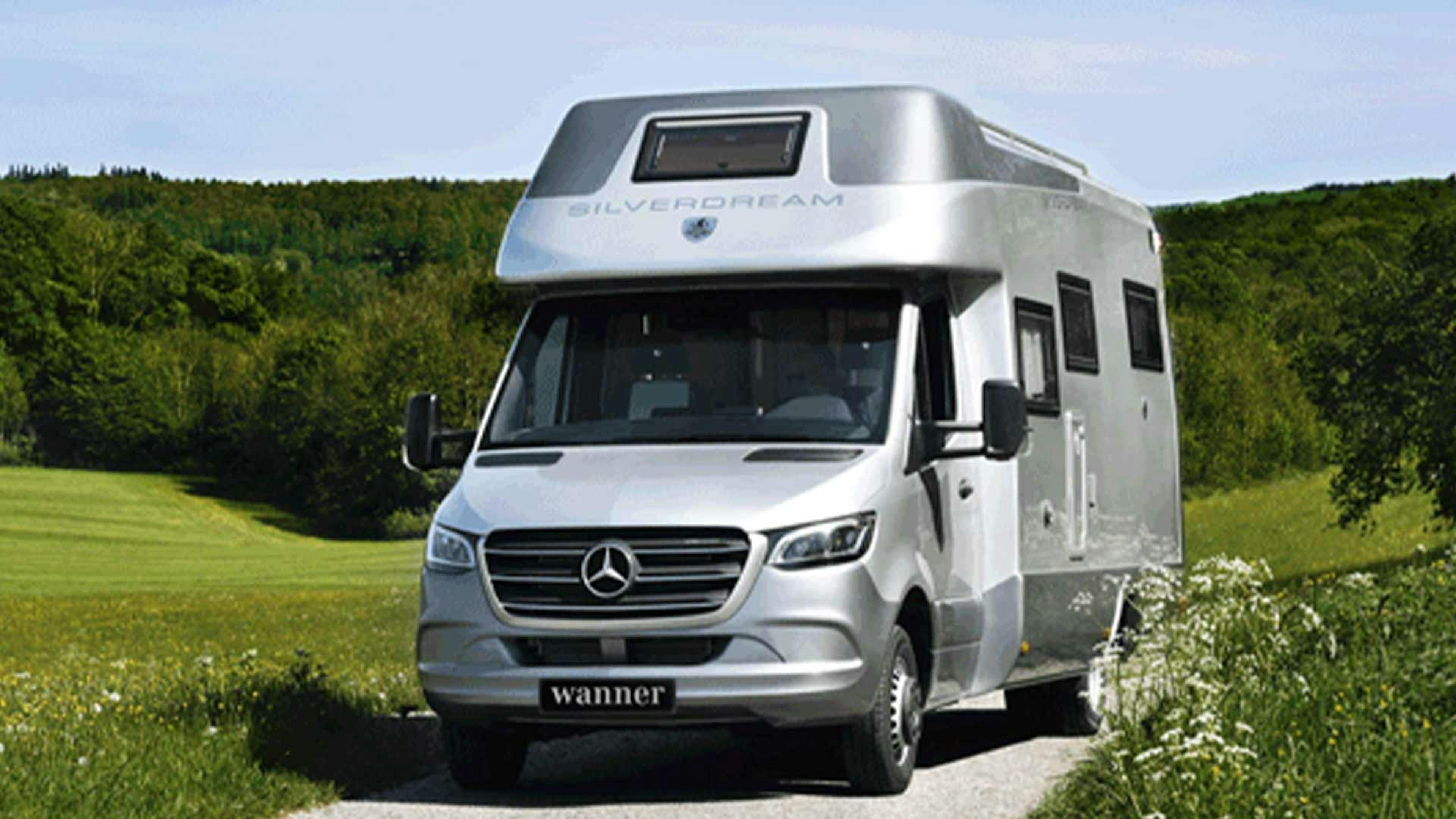 Ein Wanner Silverdream Wohnmobil mit Alkoven fährt einen Feldweg entlang.