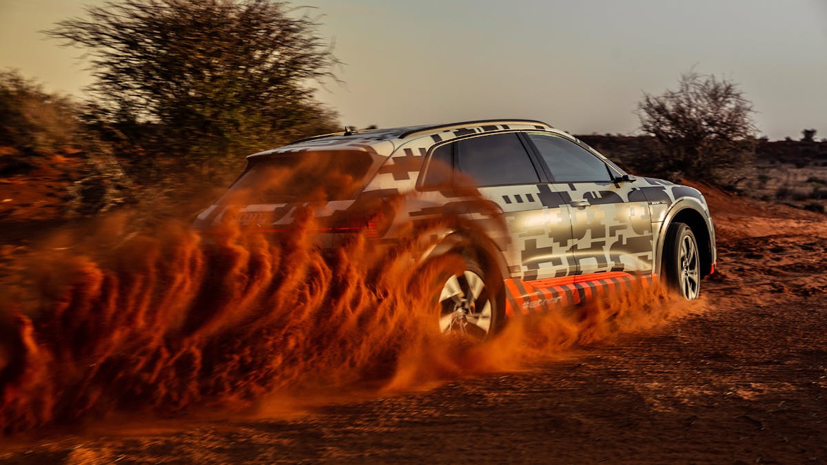 Ein schwarz-weißer Audi e-tron beschleunigt in einer wüstenartigen Landschaft