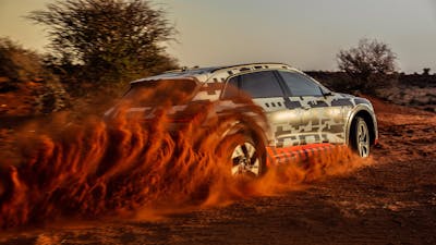 Ein schwarz-weißer Audi e-tron beschleunigt in einer wüstenartigen Landschaft