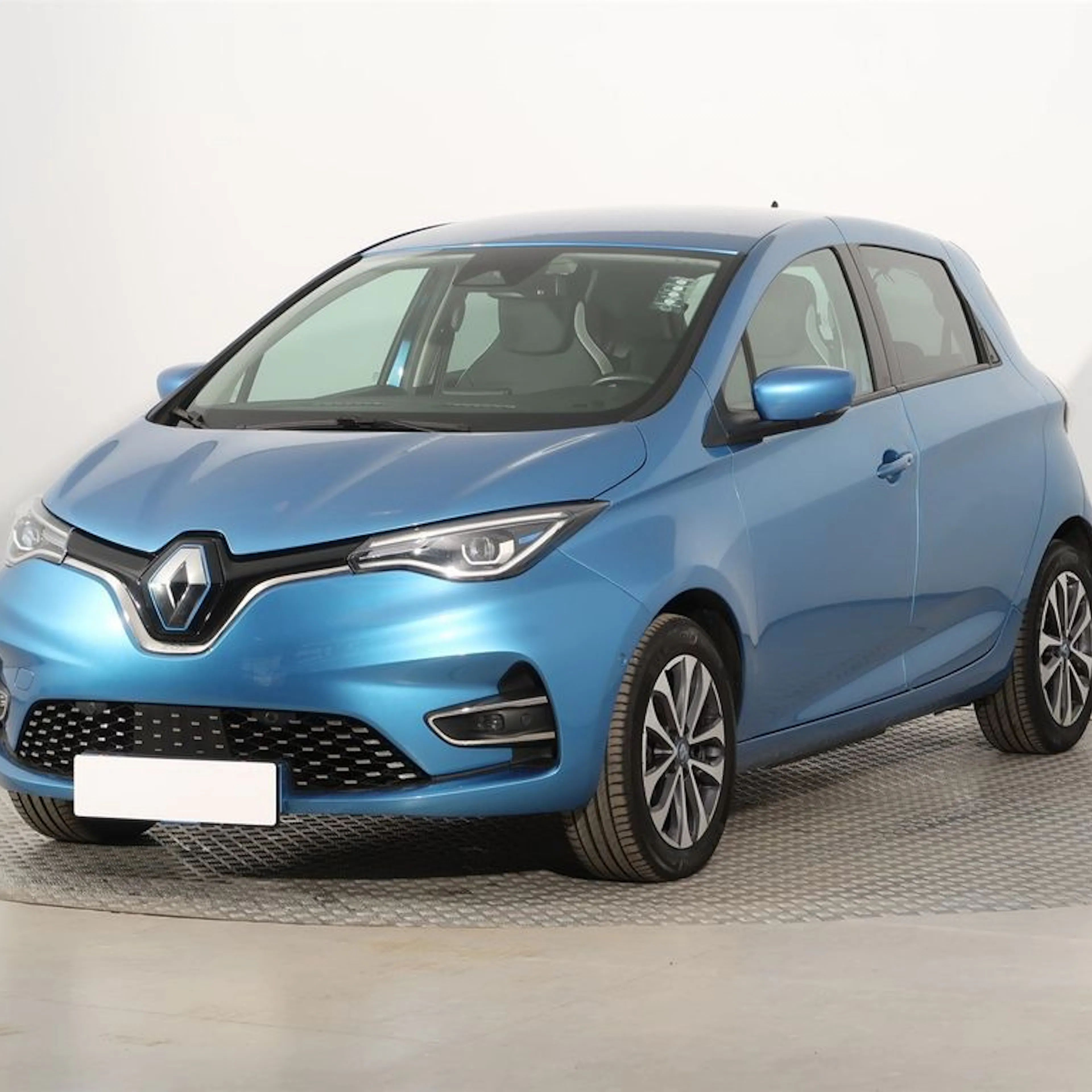 Blauer Renault Zoe, ein kompakter fünftüriger Elektro-Kleinwagen, steht in einem hellen Studio auf einer drehbaren Plattform.