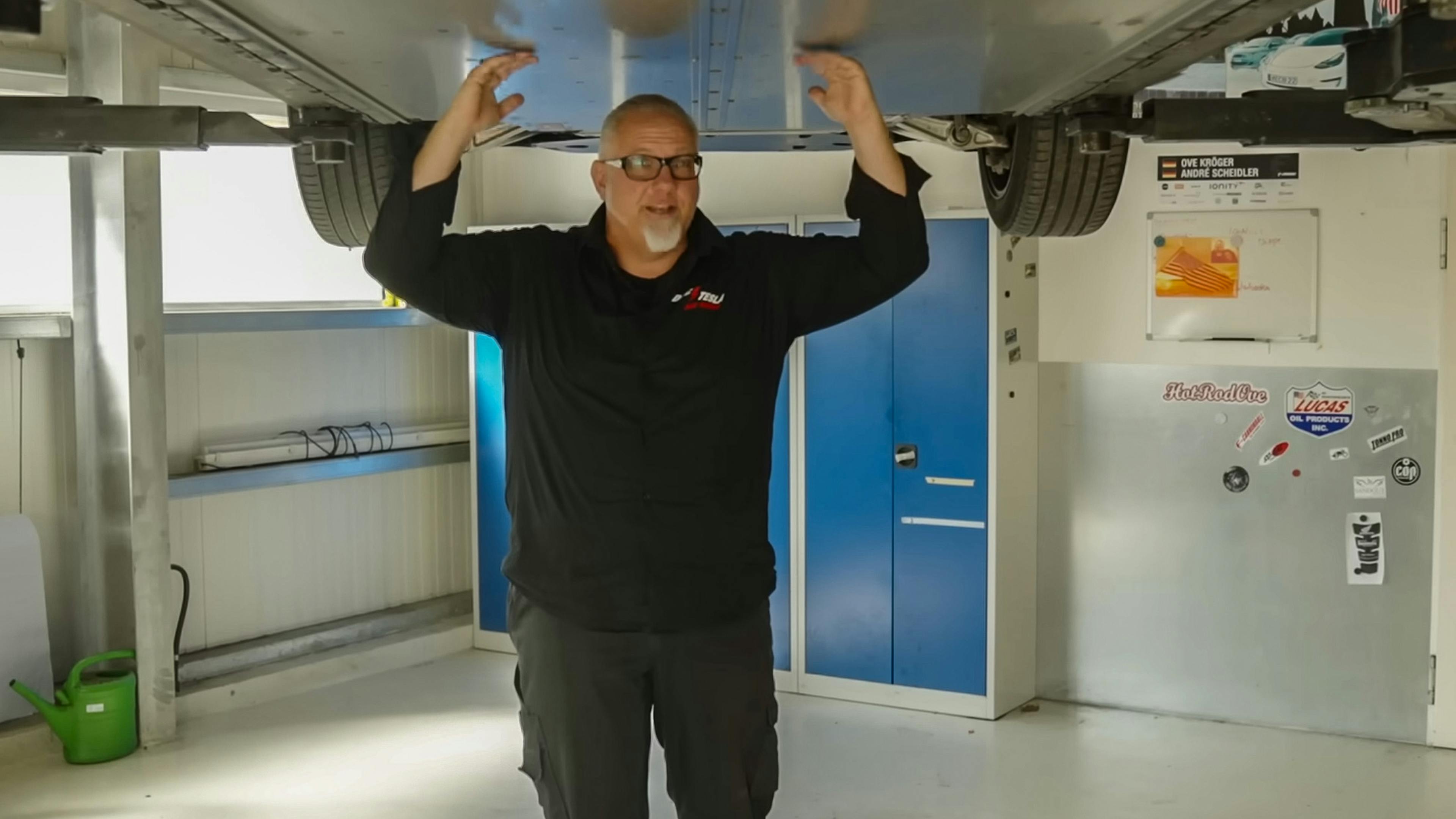 E-Auto-Experte Ove Kröger zeigt, wo bei einem Tesla Model X die Akkus im Unterboden verbaut sind. 