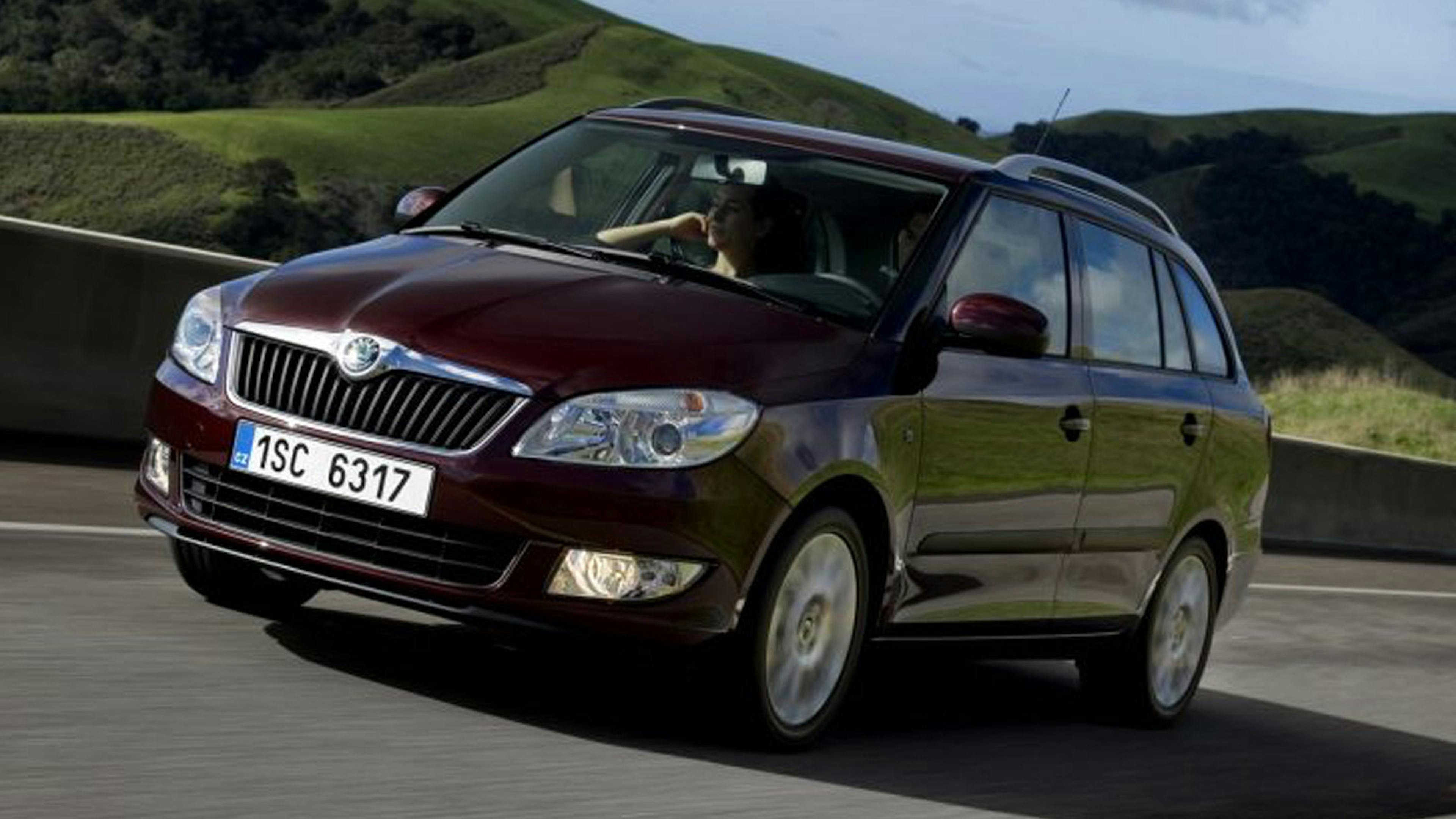 Ein weinroter Škoda Fabia Combi fährt eine Landstraße entlang.