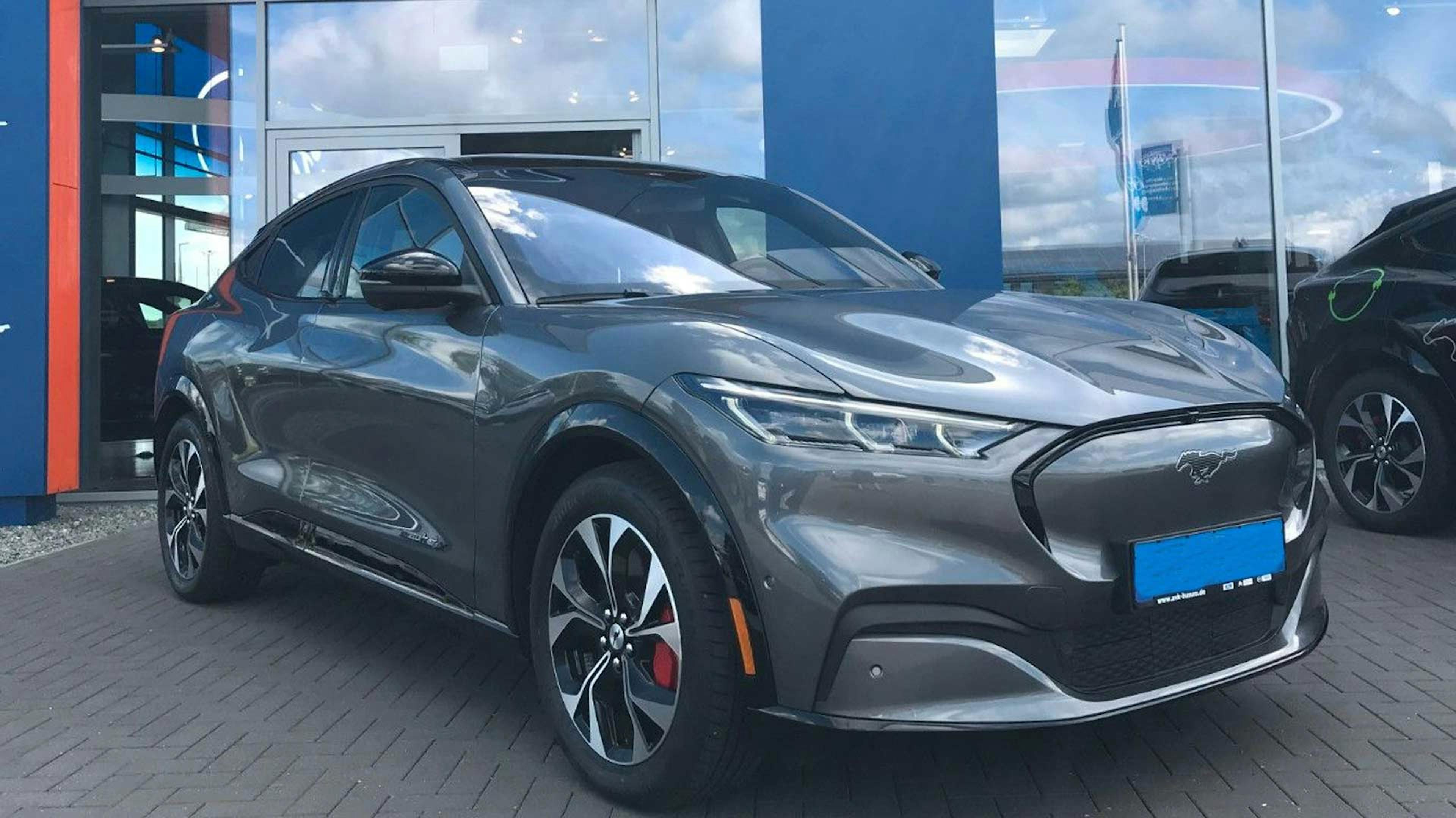 Ein dunkelgrauer Ford Mustang Mach-E Extended Range steht vor einem Autohaus.