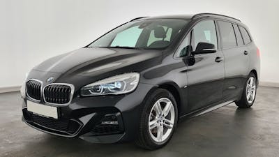 Ein schwarzer BMW 2er Gran Tourer steht vor einer weißen Wand.