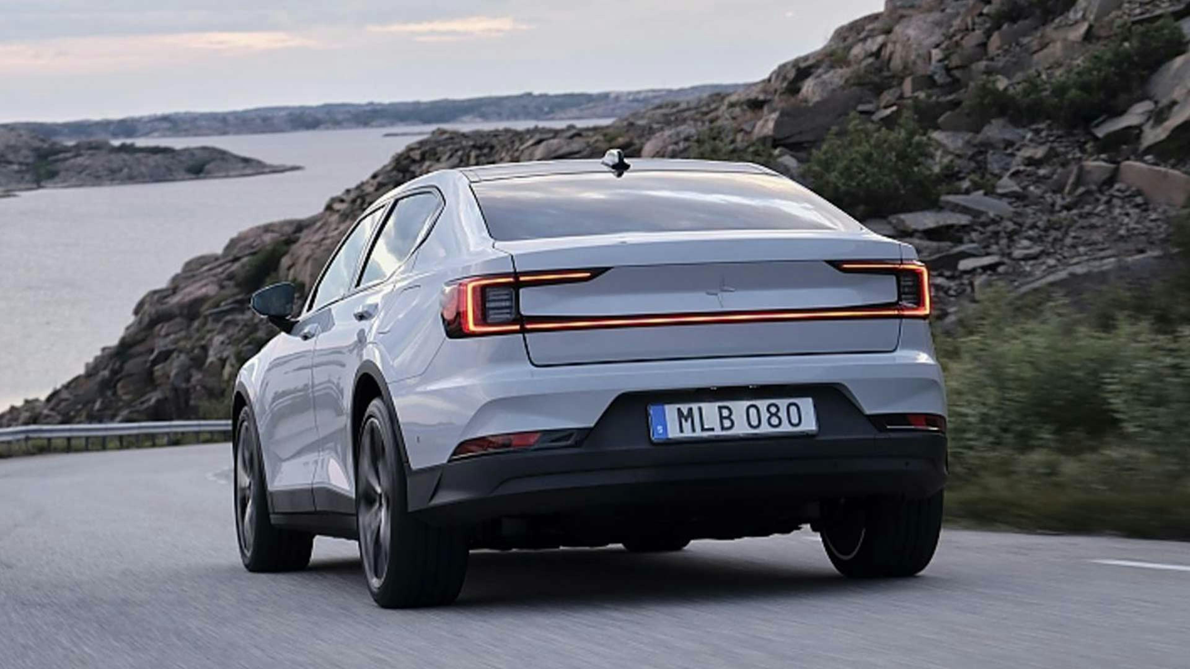 Ein graues Polestar-2-Elektroauto mit Allradantrieb fährt eine Landstraße entlang.