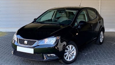 Ein schwarzer Seat Ibiza steht vor einem grauen Rolltor.