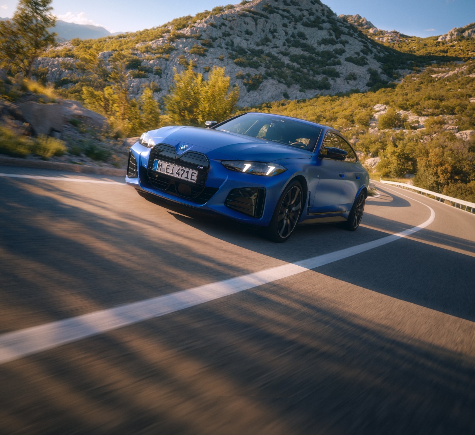 BMW i4 M60 xDrive Gran Coupé in Blau bei dynamischer Kurvenfahrt auf einer Bergstraße.