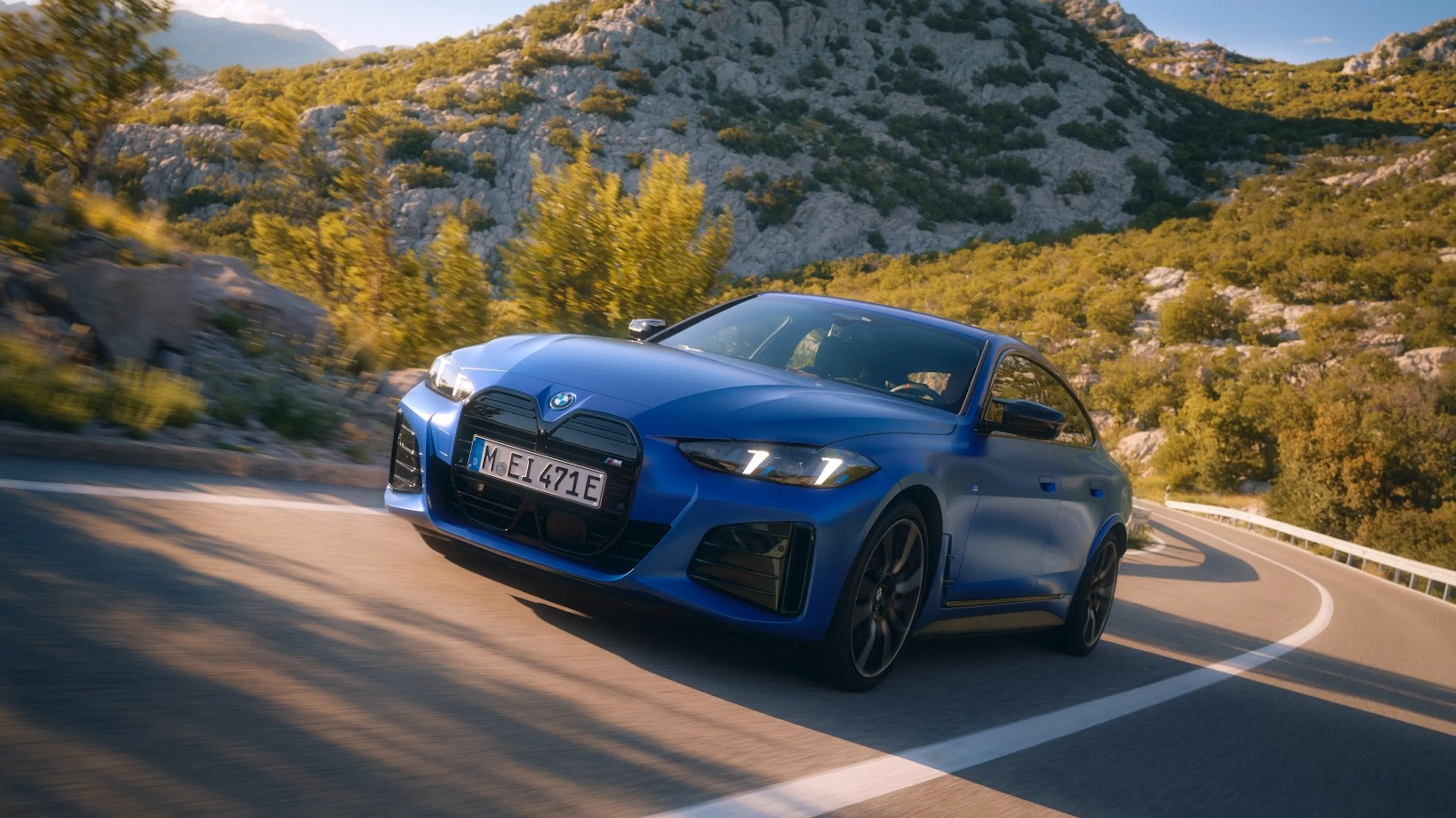 BMW i4 M60 xDrive Gran Coupé in Blau bei dynamischer Kurvenfahrt auf einer Bergstraße.