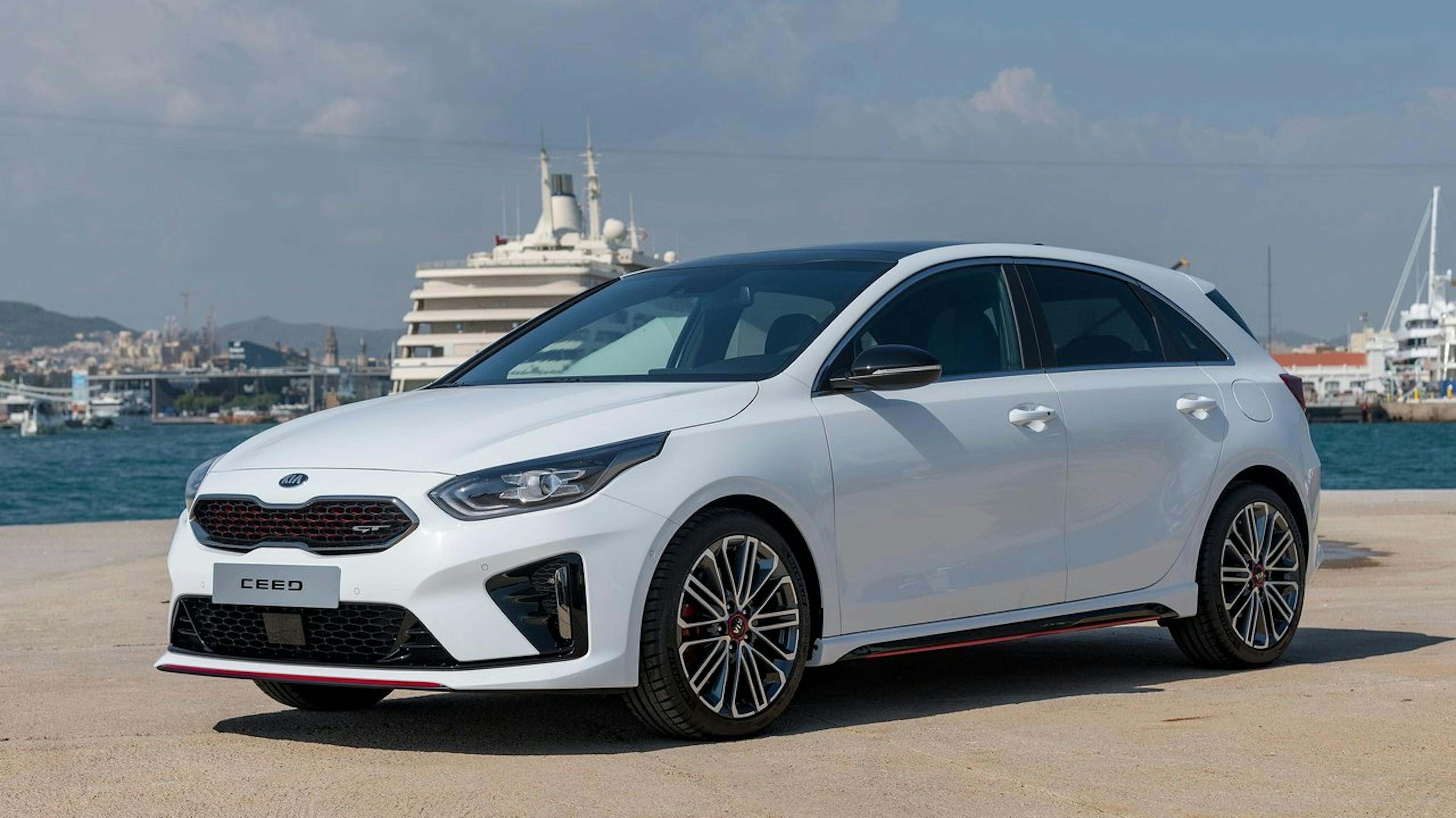 A white Kia Ceed GT is parked at a port.