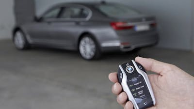 Eine Person öffnet einen grauen BMW mithilfe eines Keyless-Go-Autoschlüssels
